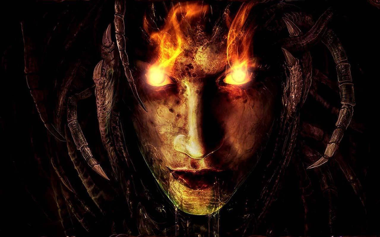 詭異的GIF 桌布 壁紙 — 一個惡魔般的面孔，帶有發光的火眼和燃燒的頭髮，從黑暗中以威脅性的特寫出現。