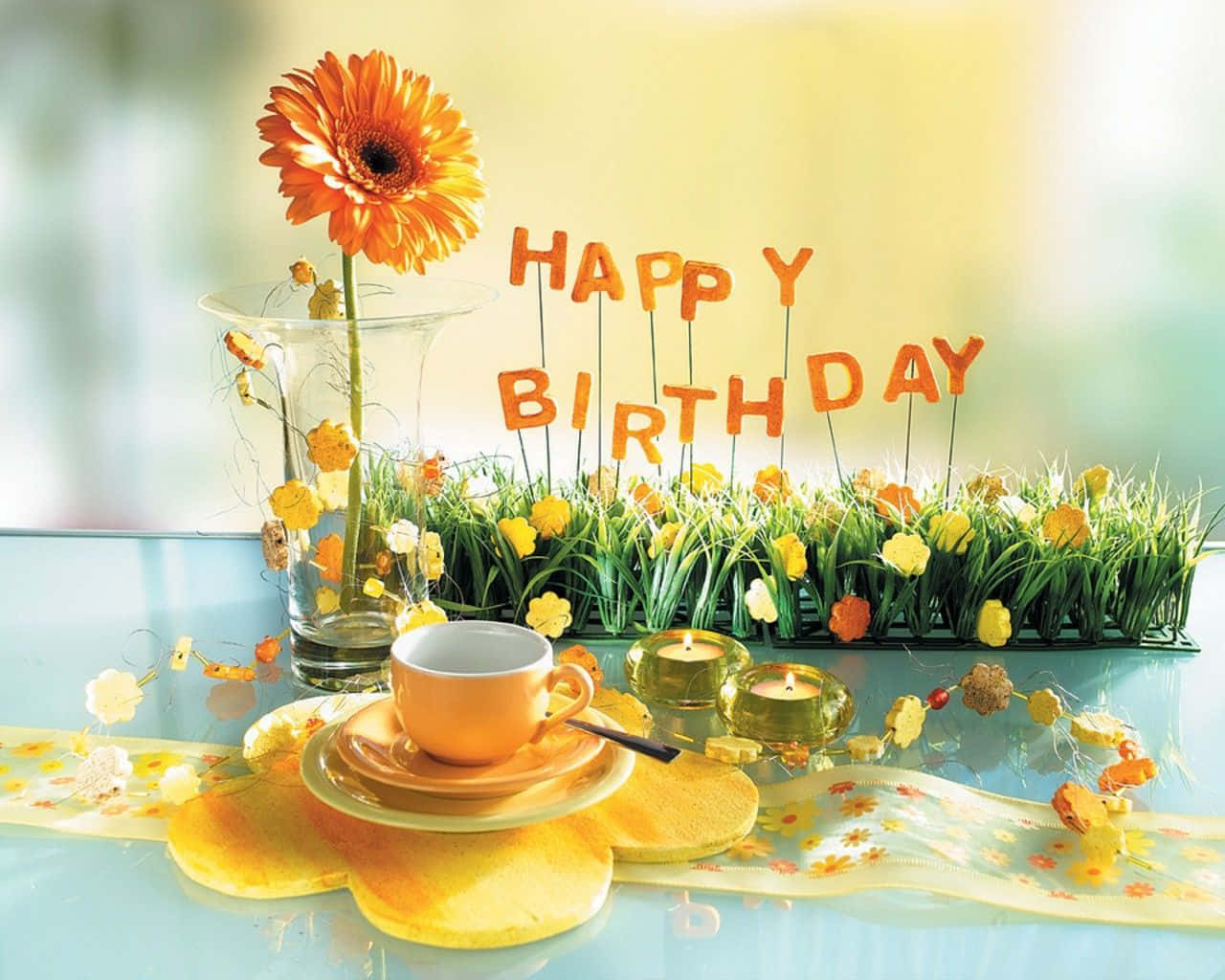生日餐桌，有橙色非洲菊、杯子、蠟燭和寫著生日快樂的草字母 — 向日葵 GIF 壁紙