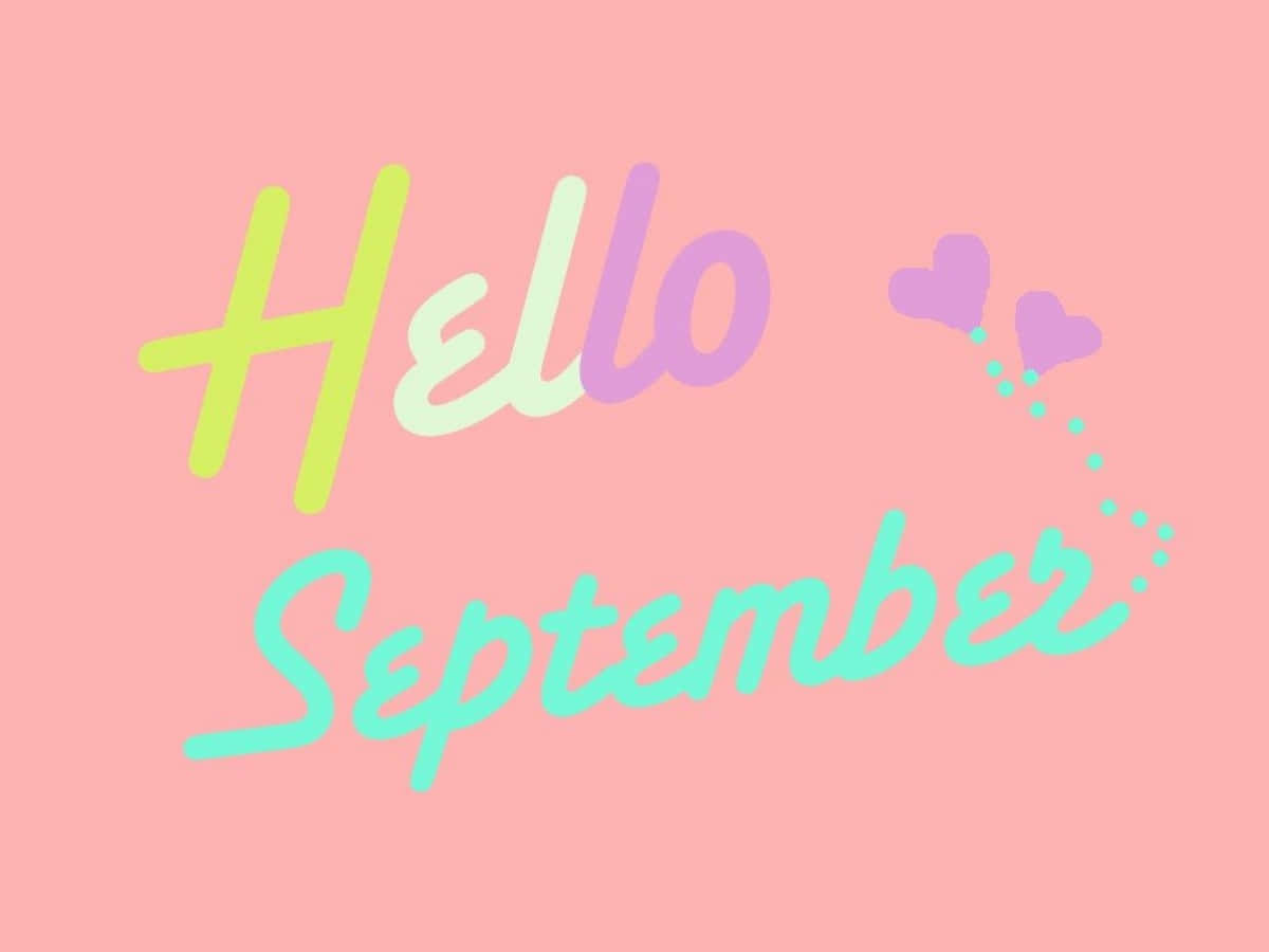 Hello 桌布 壁紙 — 一個愉快的粉彩粉紅色背景，上面有「Hello September」字樣，採用俏皮的漸變字體，並有漂浮的心形在後面。