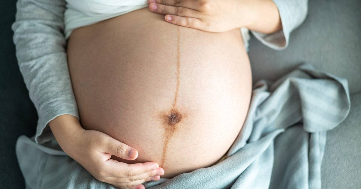 Pregnant 桌布 壁紙 — 一個懷孕肚子的特寫，雙手輕輕托住，靠在柔軟的灰色布料上。