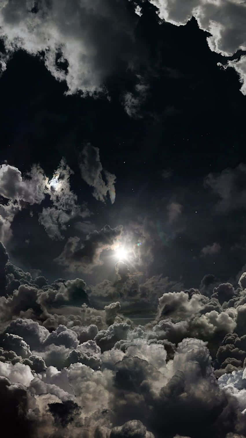自然 桌布 壁紙 — 一個戲劇性的夜空，明亮的月亮穿透密集、有紋理的雲層，顯露出遙遠的星星。