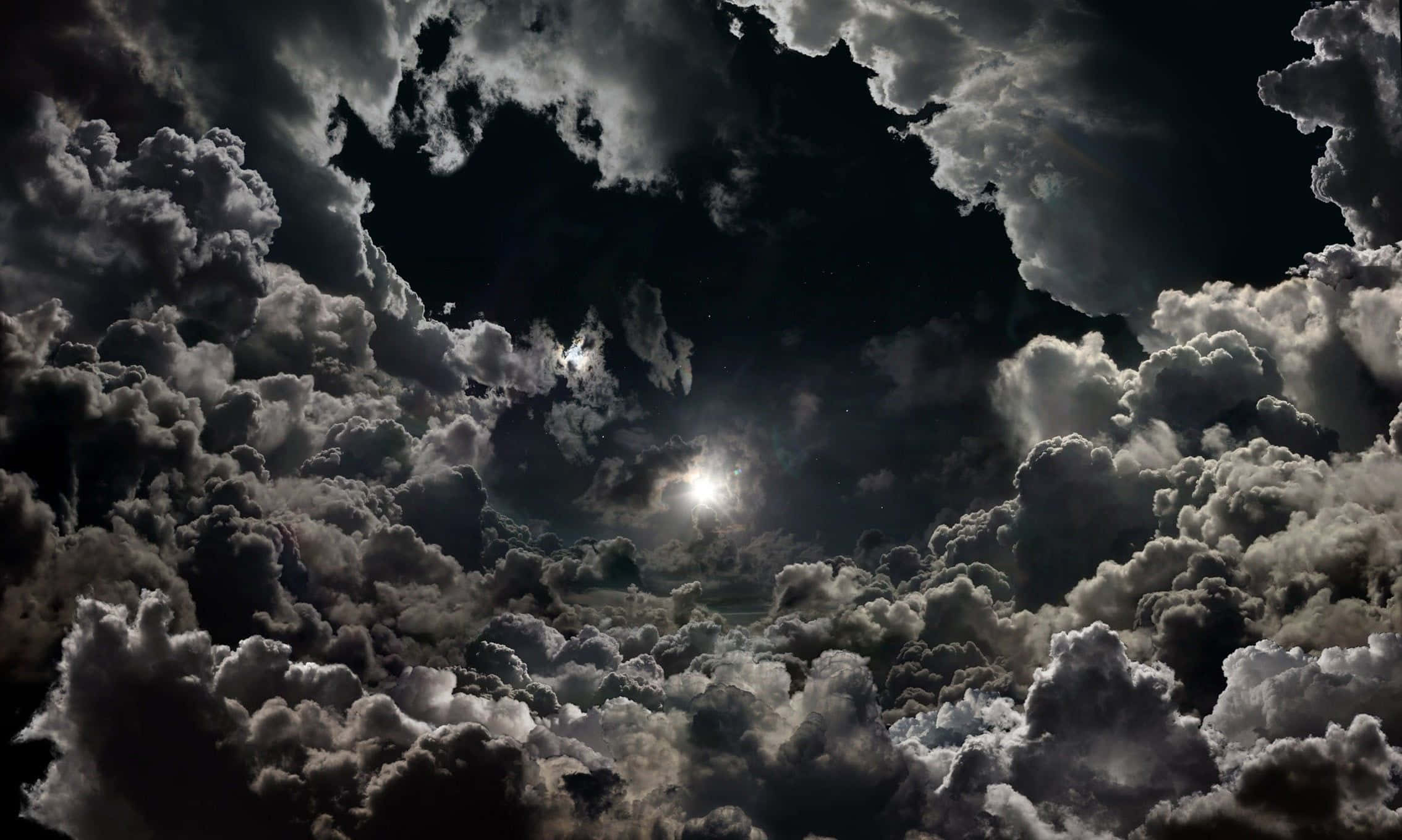 黑白 桌布 壁紙 — 一個戲劇性的夜空，明亮的月亮穿過密集的漩渦雲層照耀。