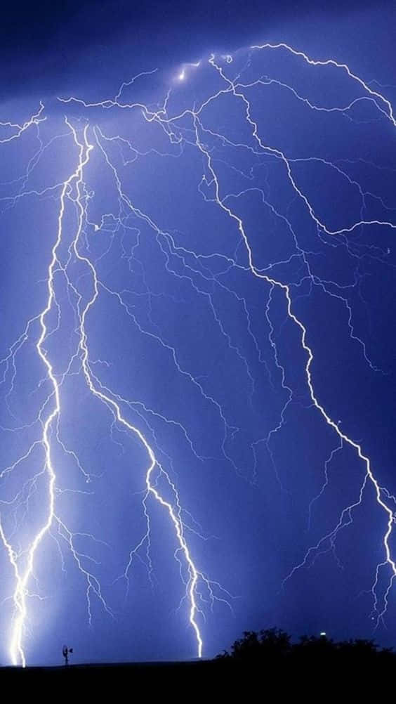 閃電 桌布 壁紙 — 一個戲劇性的天空被多道鋸齒狀閃電劈開，照亮了深藍色的暴風雨氛圍。