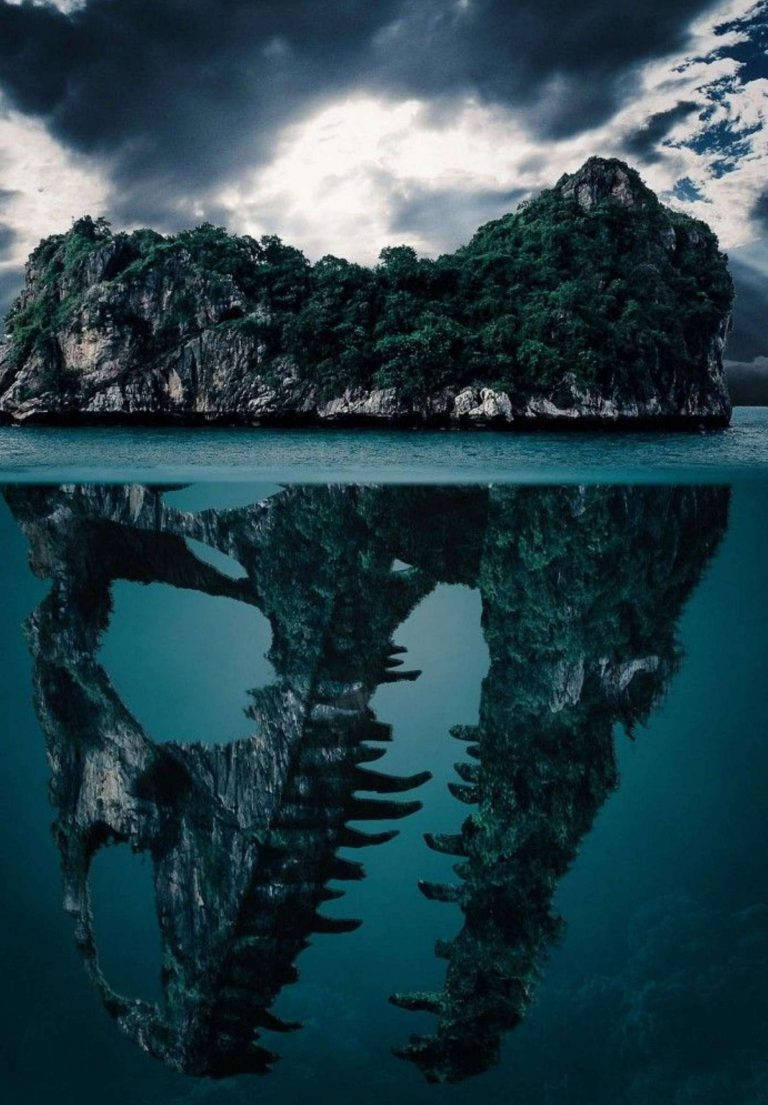 Photoshop HD 桌布 壁紙 — 一個戲劇性的岩石島嶼覆蓋著茂密的綠色植物，矗立在暴風雨的天空下，其完美的倒影映照在平靜的碧綠海水中。