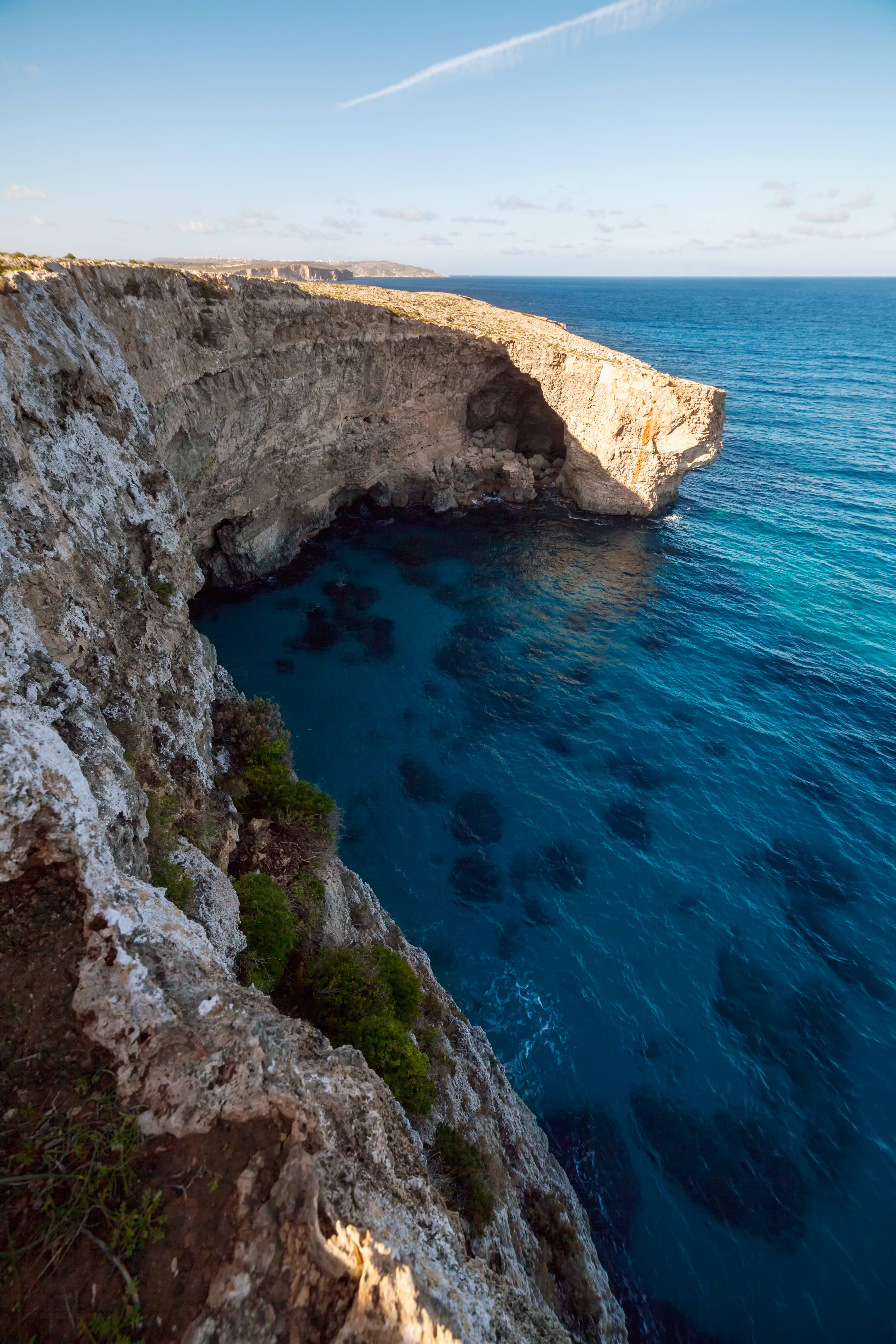 Malta 桌布 壁紙 — 一個戲劇性的懸崖洞穴通向碧綠的海水，在清澈的藍天下，有一縷薄雲。