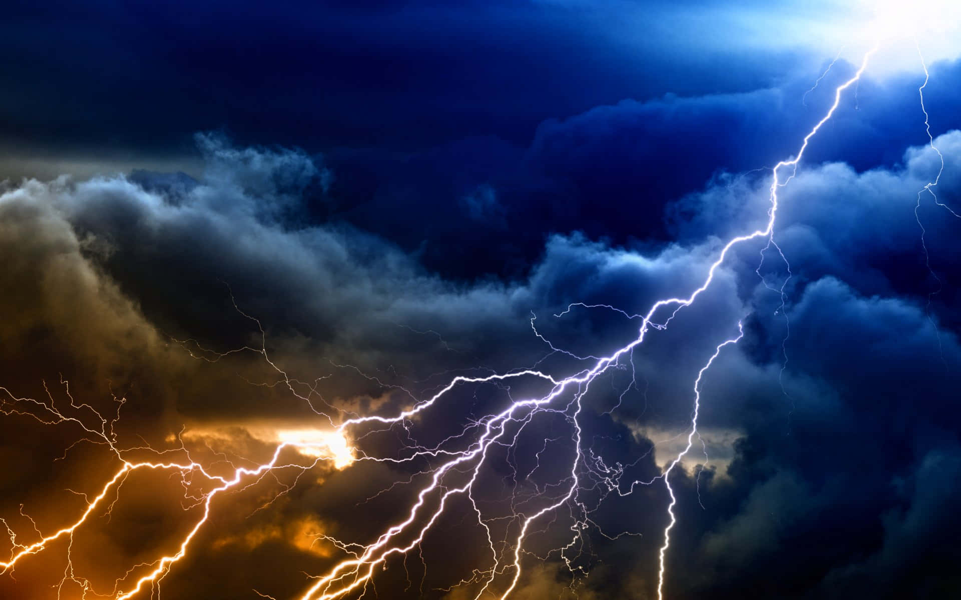 閃電 桌布 壁紙 — 一個戲劇性的暴風雨天空，被鮮明的閃電照亮，閃電以火橙色和電光藍色調劈開烏雲。