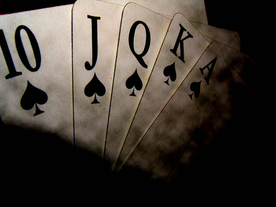 Poker 桌布 壁紙 — 一個戲劇性的特寫鏡頭，展示從十點到Ace的黑桃撲克牌扇，背景為深色。