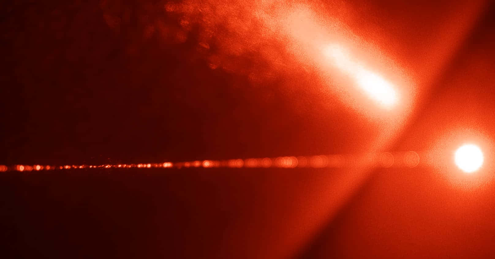 Red Light 桌布 壁紙 — 一個戲劇性的紅色調場景，明亮的光束穿過黑煙，遠處有一個發光的球體。