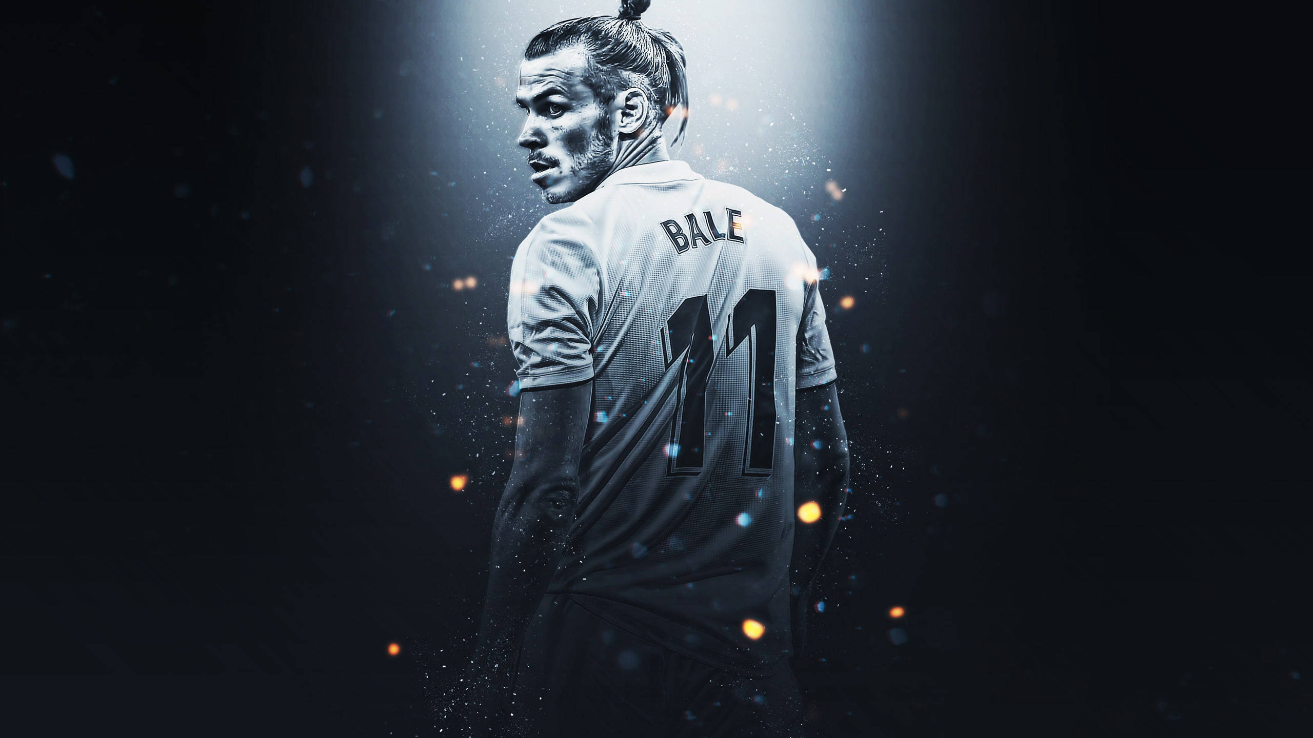 Gareth Bale 桌布 壁紙 — 一個戲劇性的聚光燈照亮了一名身穿白色球衣、印有「BALE」和11號的足球運動員，周圍是發光粒子，背景黑暗。
