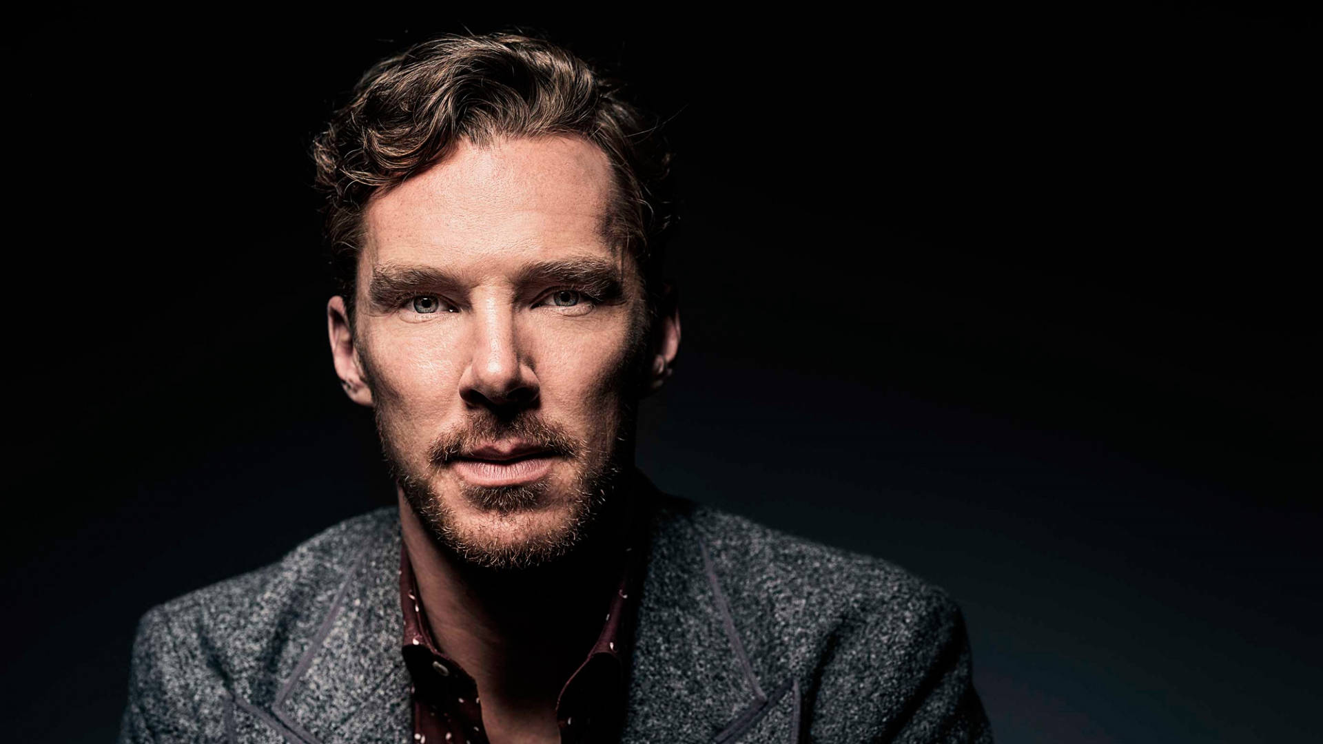 benedict 桌布 壁紙 — 一個戲劇性的肖像，一個男人帶著強烈的眼神和質感外套，背景是黑暗的。