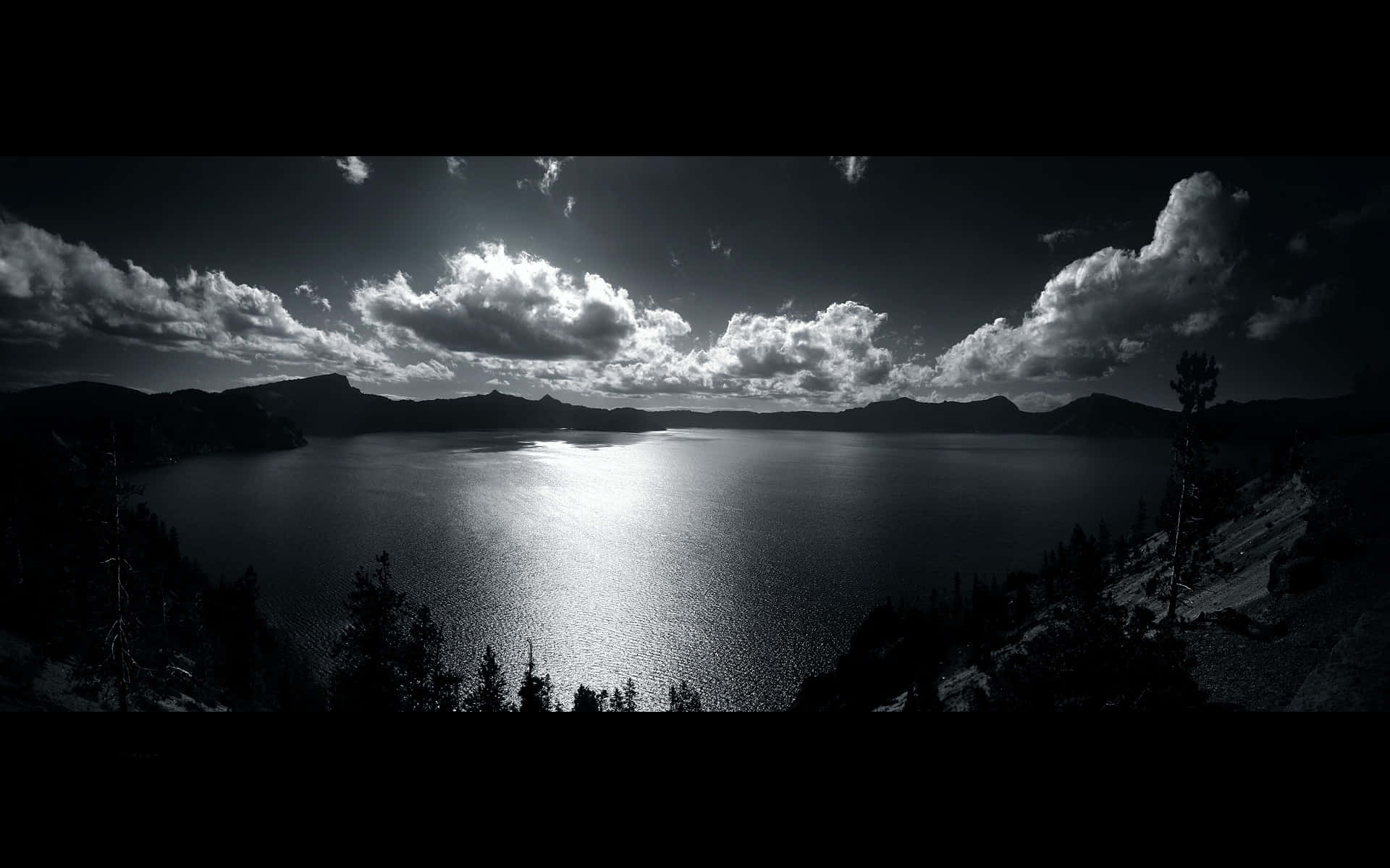 Black And White Cloud 桌布 壁紙 — 一個戲劇性的黑白全景，展現廣闊湖泊透過暴風雲反射陽光，襯以剪影樹木和遠山。