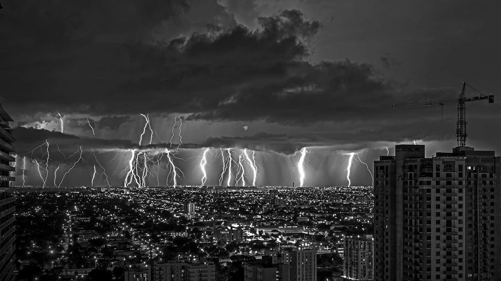 暴風 桌布 壁紙 — 一個戲劇性的黑白城市夜景，被巨大的雷暴照亮城市天際線。