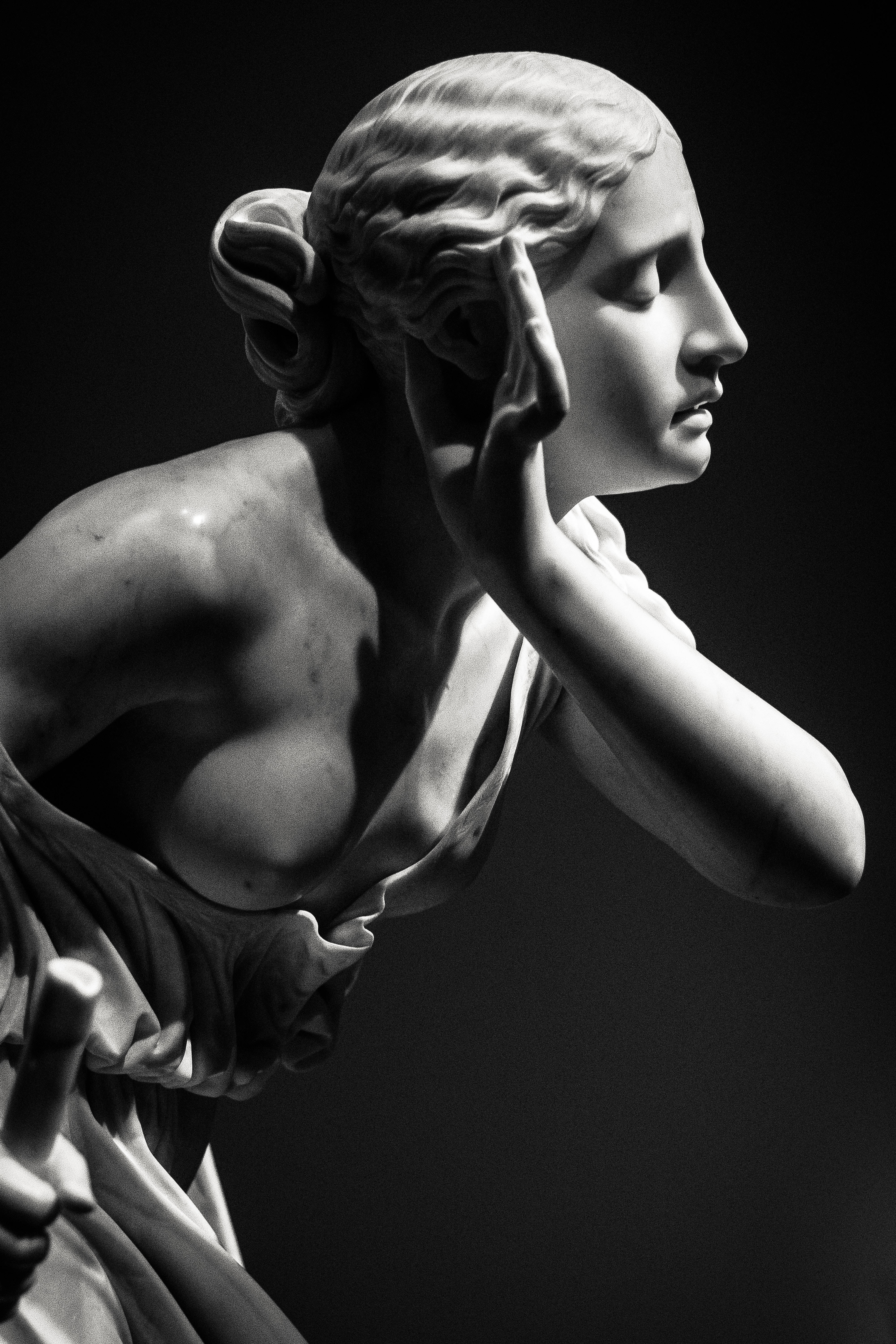 Sculpture 桌布 壁紙 — 一個戲劇性的黑白大理石雕像，描繪一位古典女性，飄逸的頭髮遮住耳朵，呈現沉思姿態。