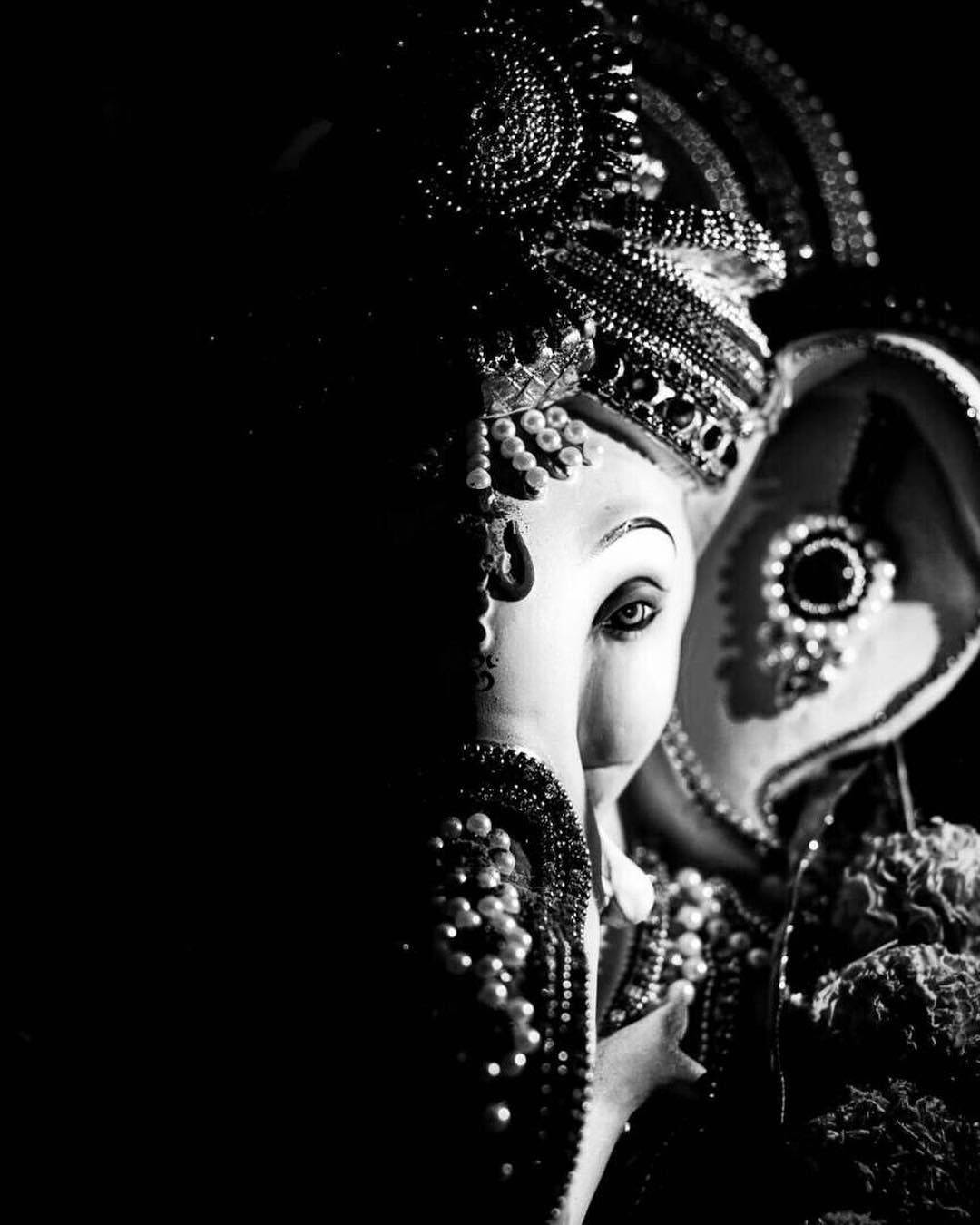 Ganesh 桌布 壁紙 — 一個戲劇性的黑白特寫，展示一尊鑲有珠寶的象頭神雕像，帶有複雜的珠飾和一個可見的眼睛。