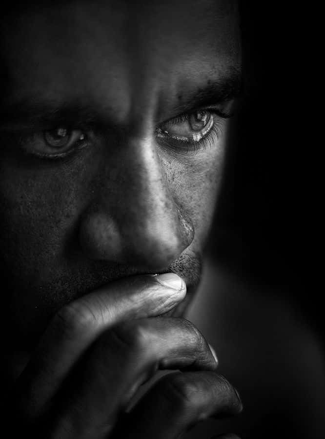 emotion 桌布 壁紙 — 一個戲劇性的黑白特寫，捕捉男人銳利的眼睛和陰影中靠近嘴巴的手。