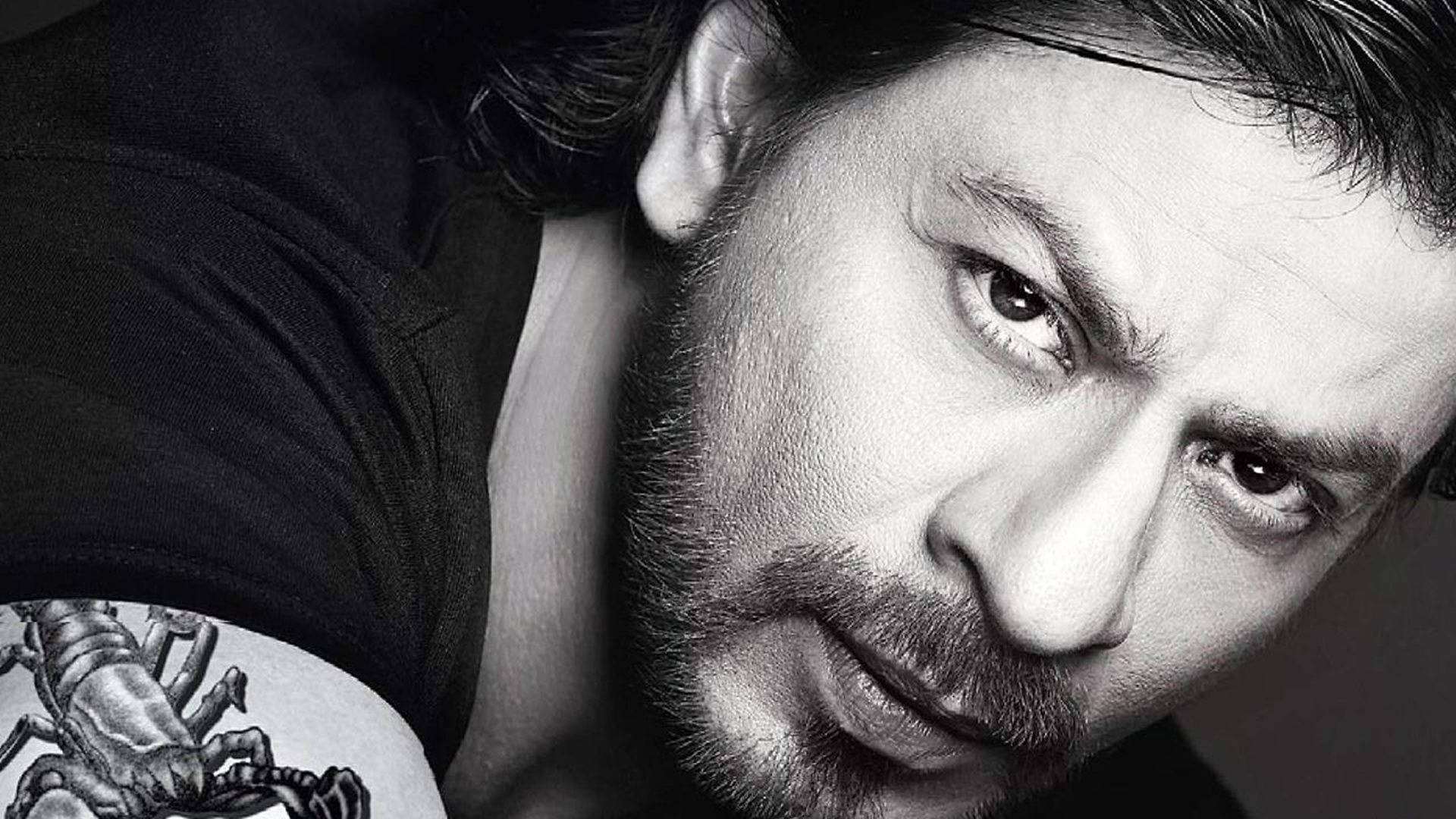 Shah Rukh Khan 桌布 壁紙 — 一個戲劇性的黑白特寫肖像，一個眼神銳利、肩上紋有蠍子紋身的男人。