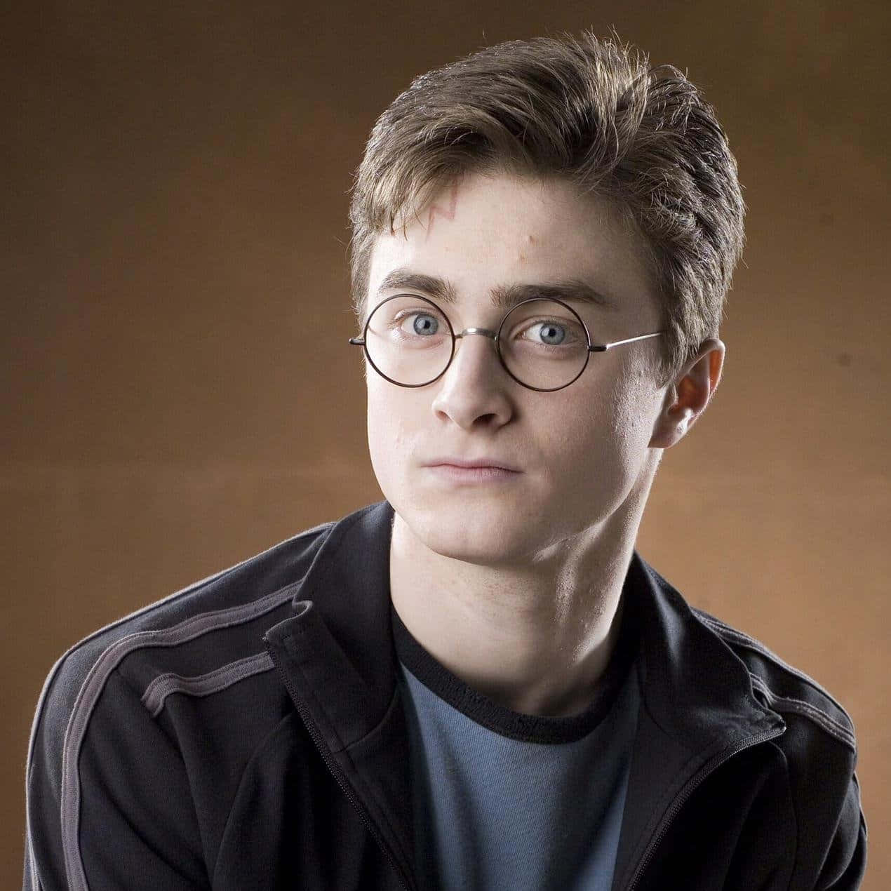 Harry Potter Profile 桌布 壁紙 — 一個戴圓框眼鏡、額頭有疤痕的年輕男子，在溫暖的棕色背景下專注地凝視。