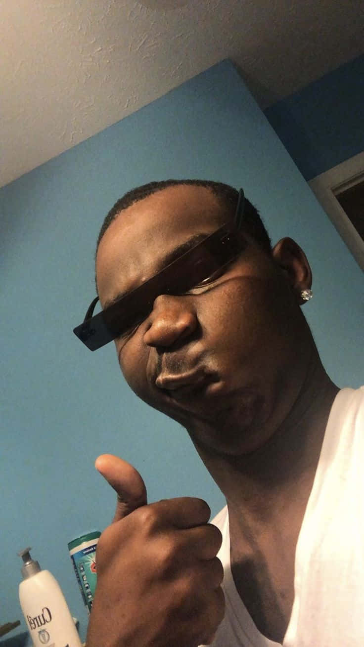 有趣美學GIF 桌布 壁紙 — 一個戴太陽眼鏡的男人對著藍色牆豎起大拇指，牆上可見浴室用品。