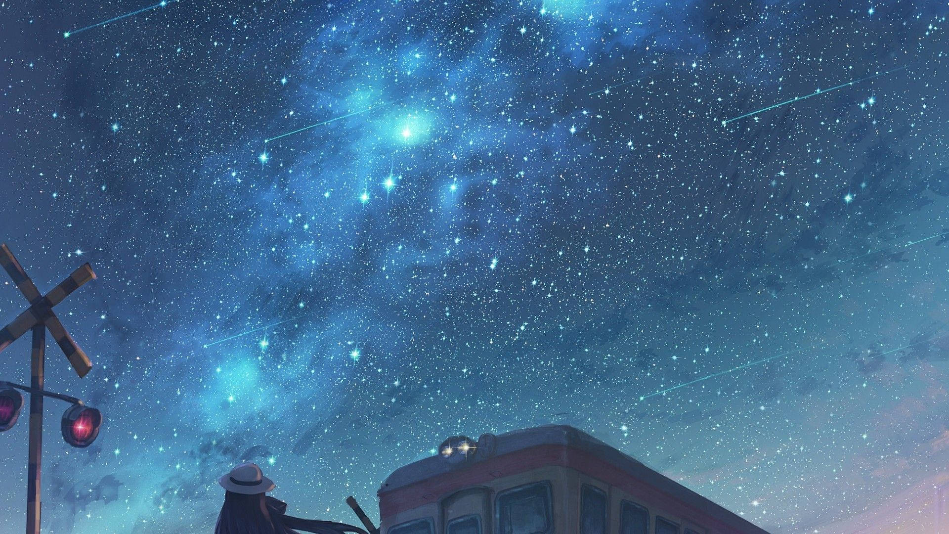 夜空 桌布 壁紙 — 一個戴帽子的孤獨身影仰望火車和鐵路平交道上方充滿流星的鮮豔藍色星空。