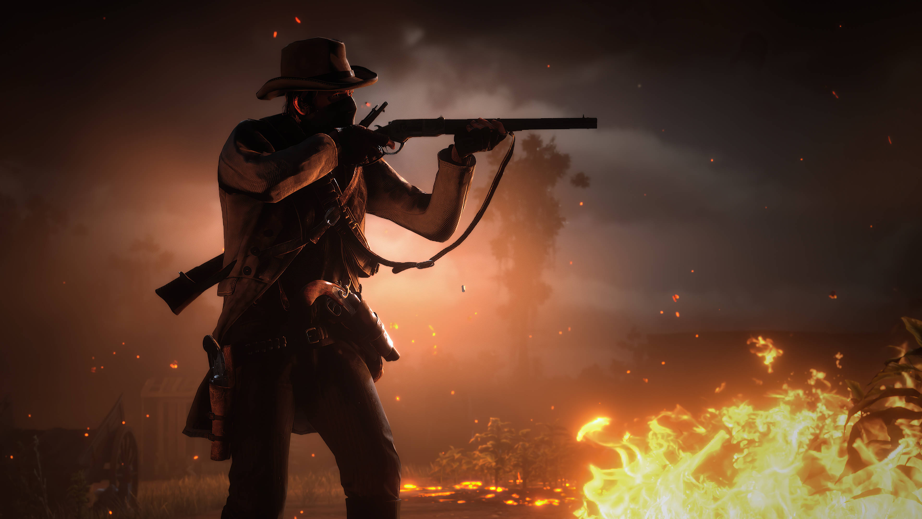 Red Dead Redemtion 2 桌布 壁紙 — 一個戴帽子的牛仔在煙霧和火星飄浮的熾熱日落背景下瞄準步槍。