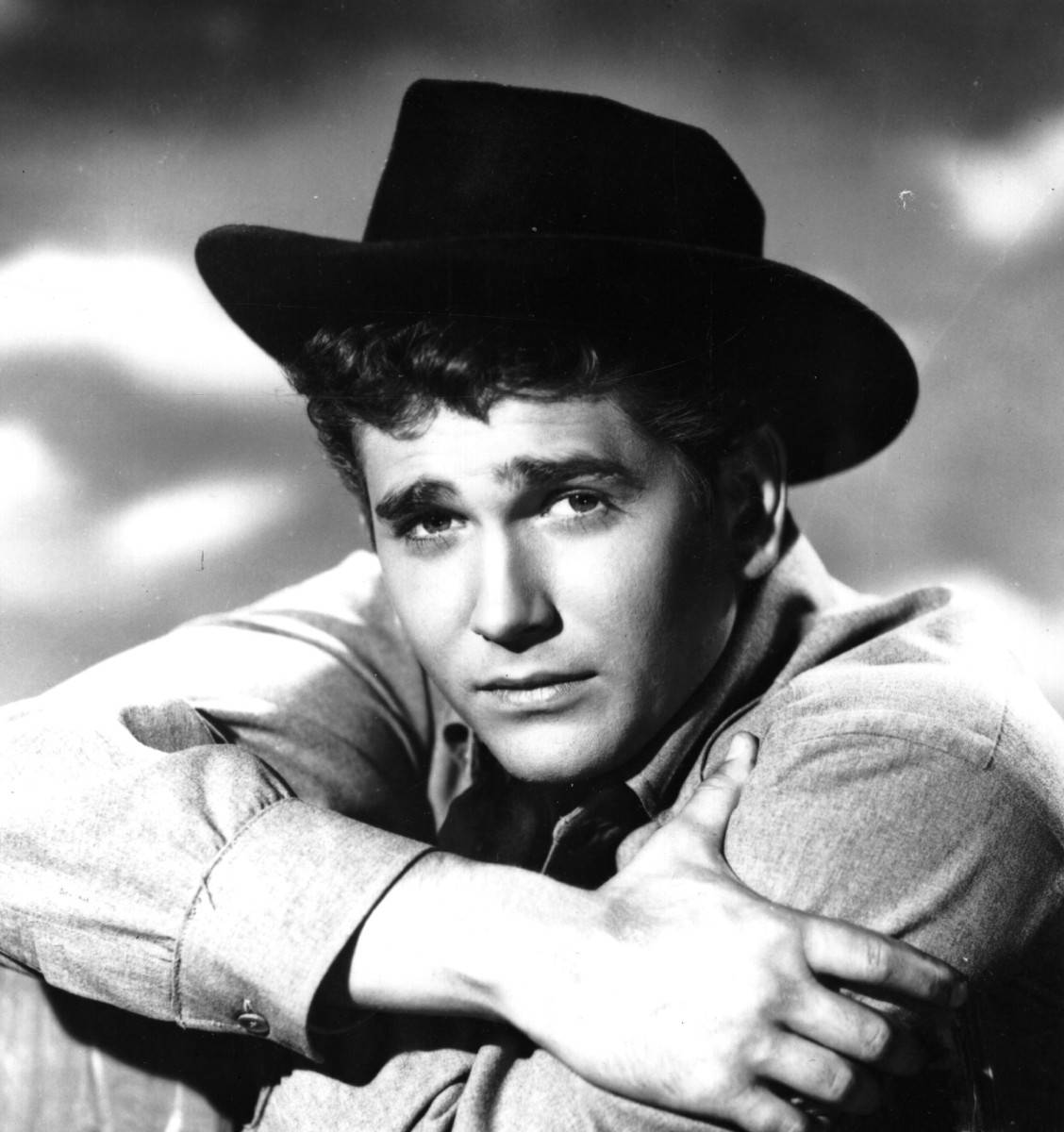 Michael Landon 桌布 壁紙 — 一個戴牛仔帽的年輕男子交叉雙臂直視鏡頭的黑白肖像。