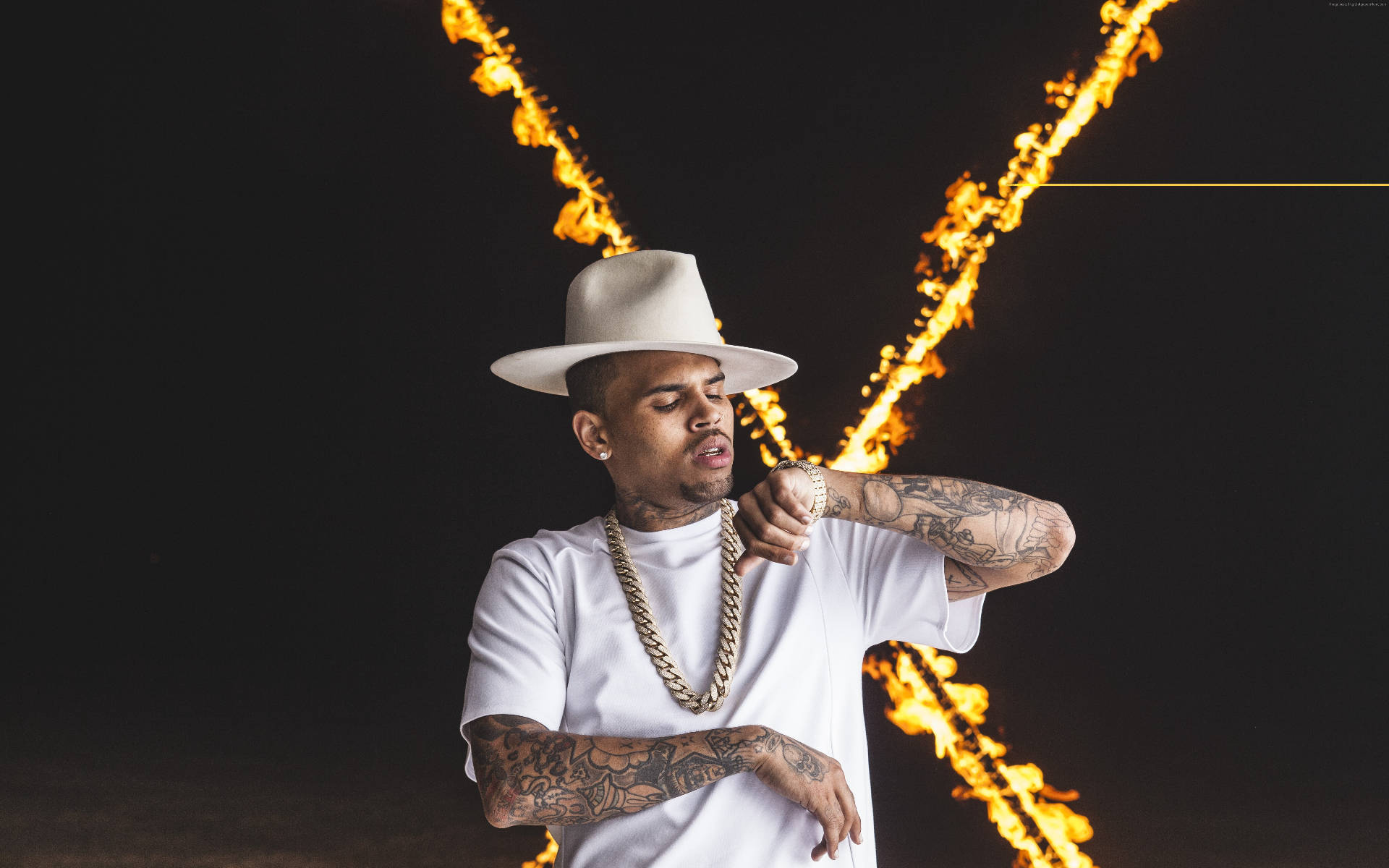 Chris Brown 桌布 壁紙 — 一個戴白色帽子和穿T恤的男人自信地指著，身後有火熱的條紋在黑暗背景下彎曲。