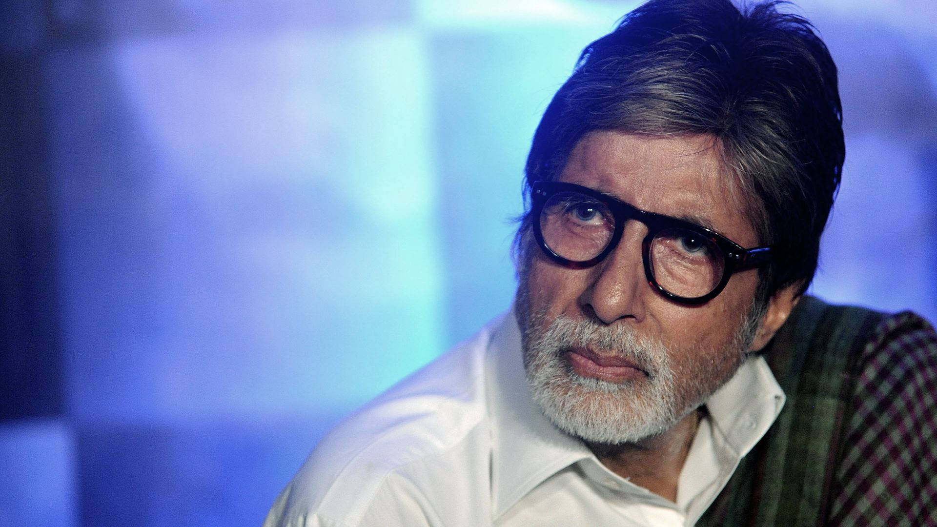 Amitabh Bachchan 桌布 壁紙 — 一個戴眼鏡、留白鬍子的男人特寫肖像，背景是模糊的藍色。
