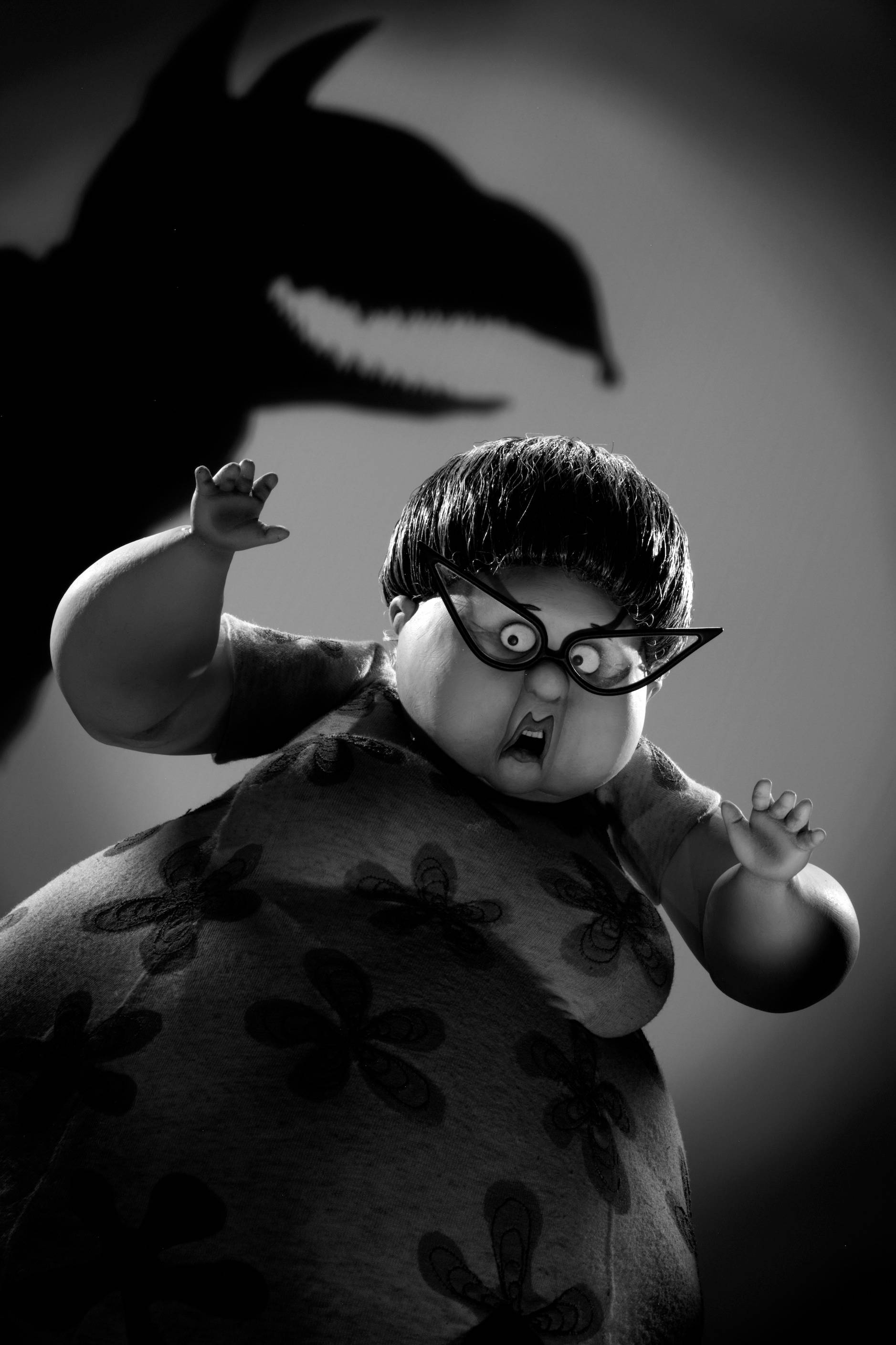Frankenweenie 桌布 壁紙 — 一個戴眼鏡、穿花卉連衣裙的黑白3D渲染動畫角色尖叫，身後有一個怪物般的陰影若隱若現。