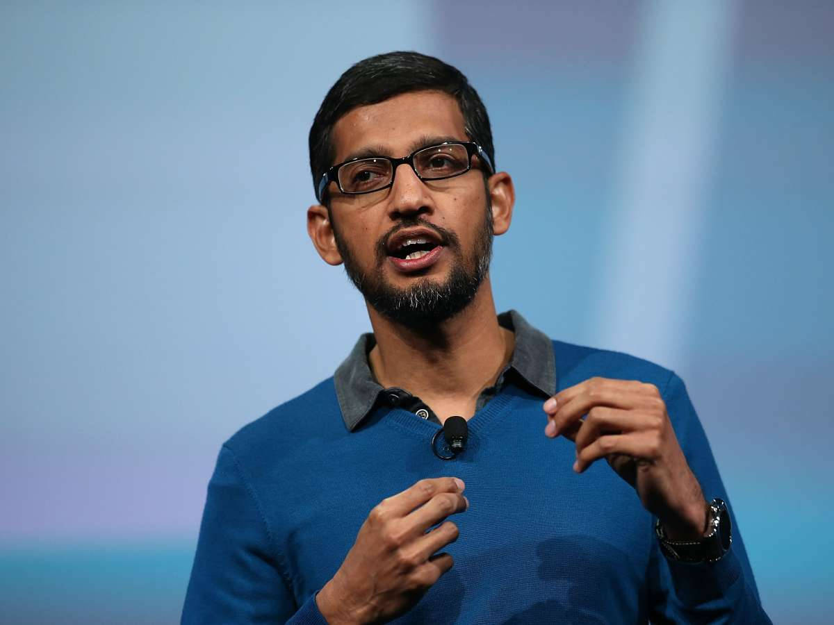 google 桌布 壁紙 — 一個戴眼鏡和鬍鬚的男人在柔和的藍色背景前熱情地說話並做手勢。