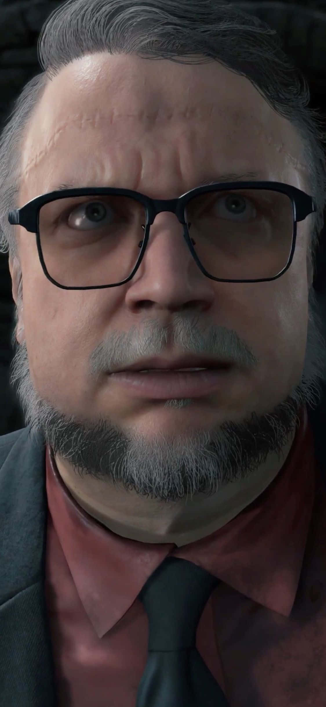 iPhone X Death Stranding 桌布 壁紙 — 一個戴眼鏡和鬍鬚的男人穿著西裝和領帶的特寫，在昏暗的環境中。