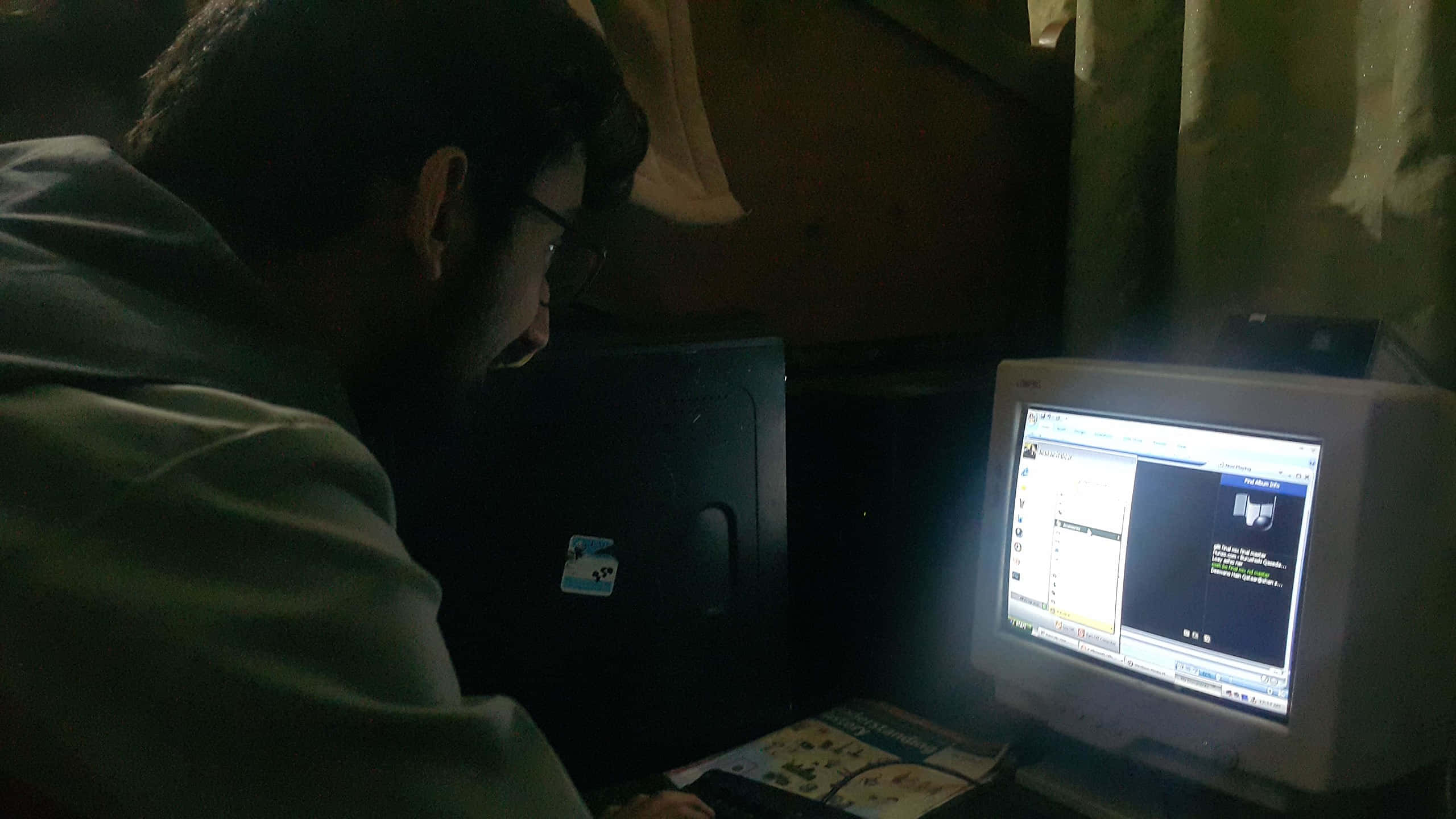 Working 桌布 壁紙 — 一個戴眼鏡的人俯身靠近一個在昏暗房間中發光的舊CRT顯示器，附近有窗簾和電腦主機。