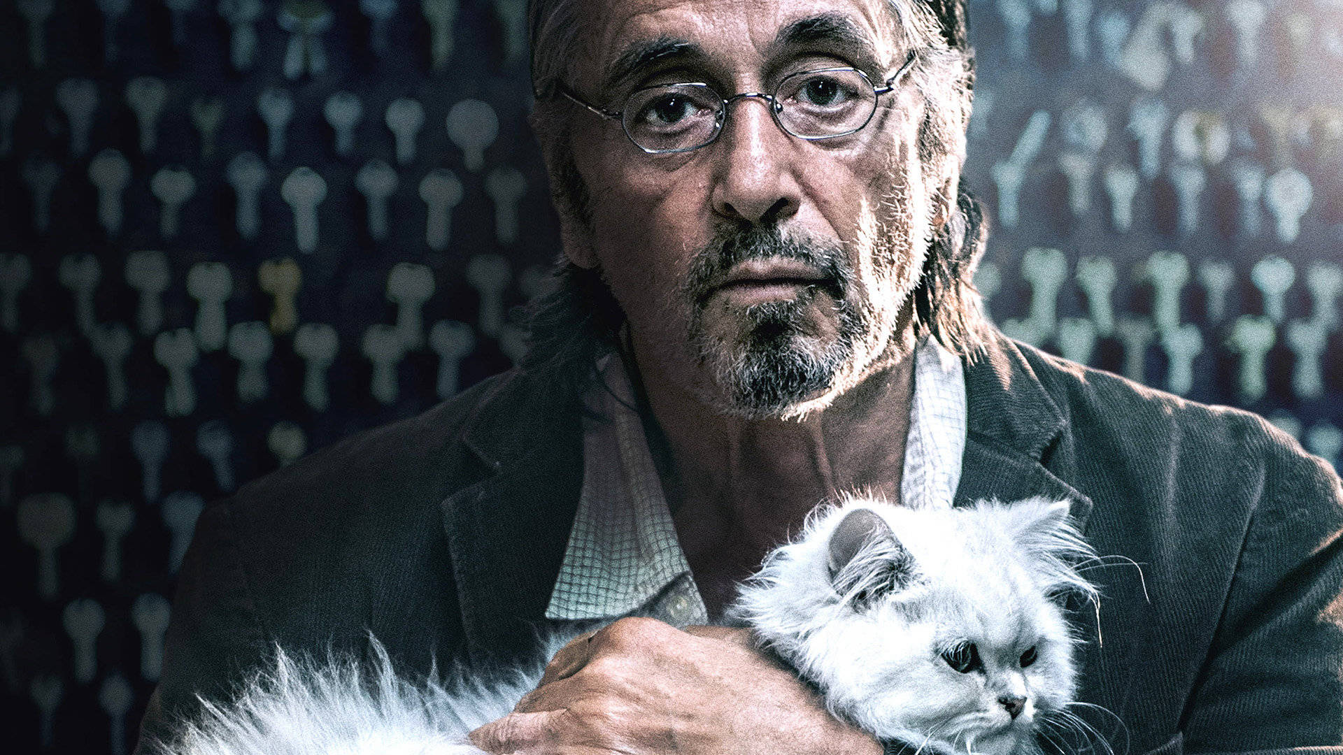 Al Pacino 桌布 壁紙 — 一個戴眼鏡的男人在昏暗燈光下，抱著一隻毛茸茸的白貓，背景是重複的鑰匙圖案。