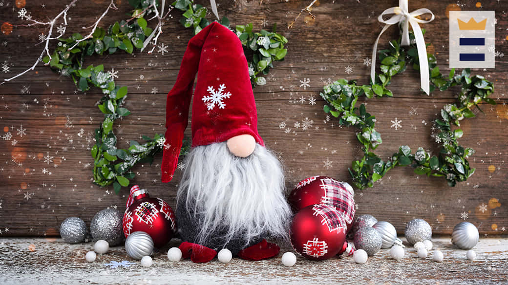 Christmas Gnome 桌布 壁紙 — 一個戴紅帽、長灰鬍子的節日地精坐在鄉村風木質表面上，周圍環繞著裝飾品和綠色花環。