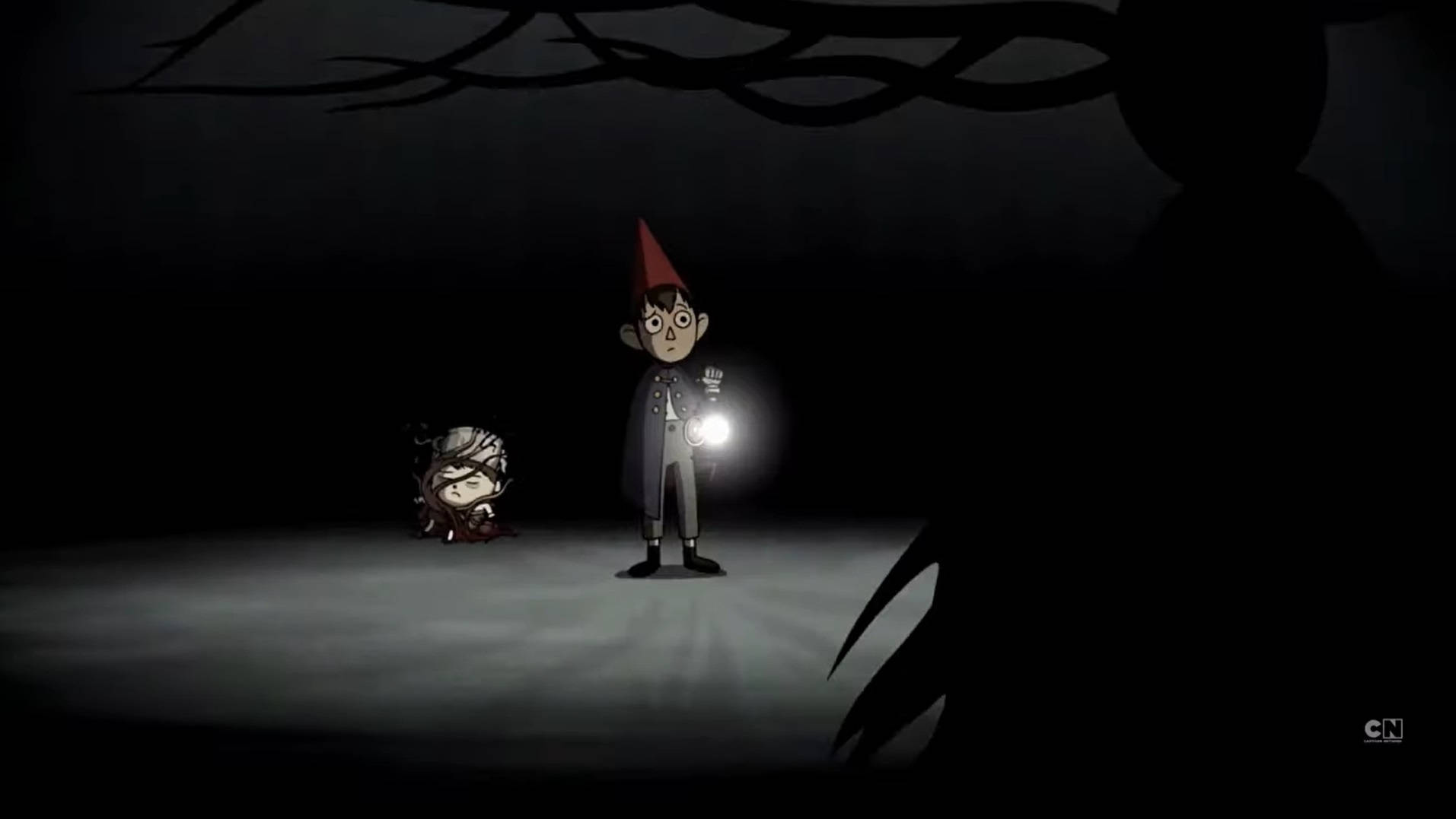 over the garden wall 桌布 壁紙 — 一個戴紅帽的小動畫男孩拿著手電筒，照亮了黑暗詭異的森林地面，頭頂上有扭曲的樹枝。