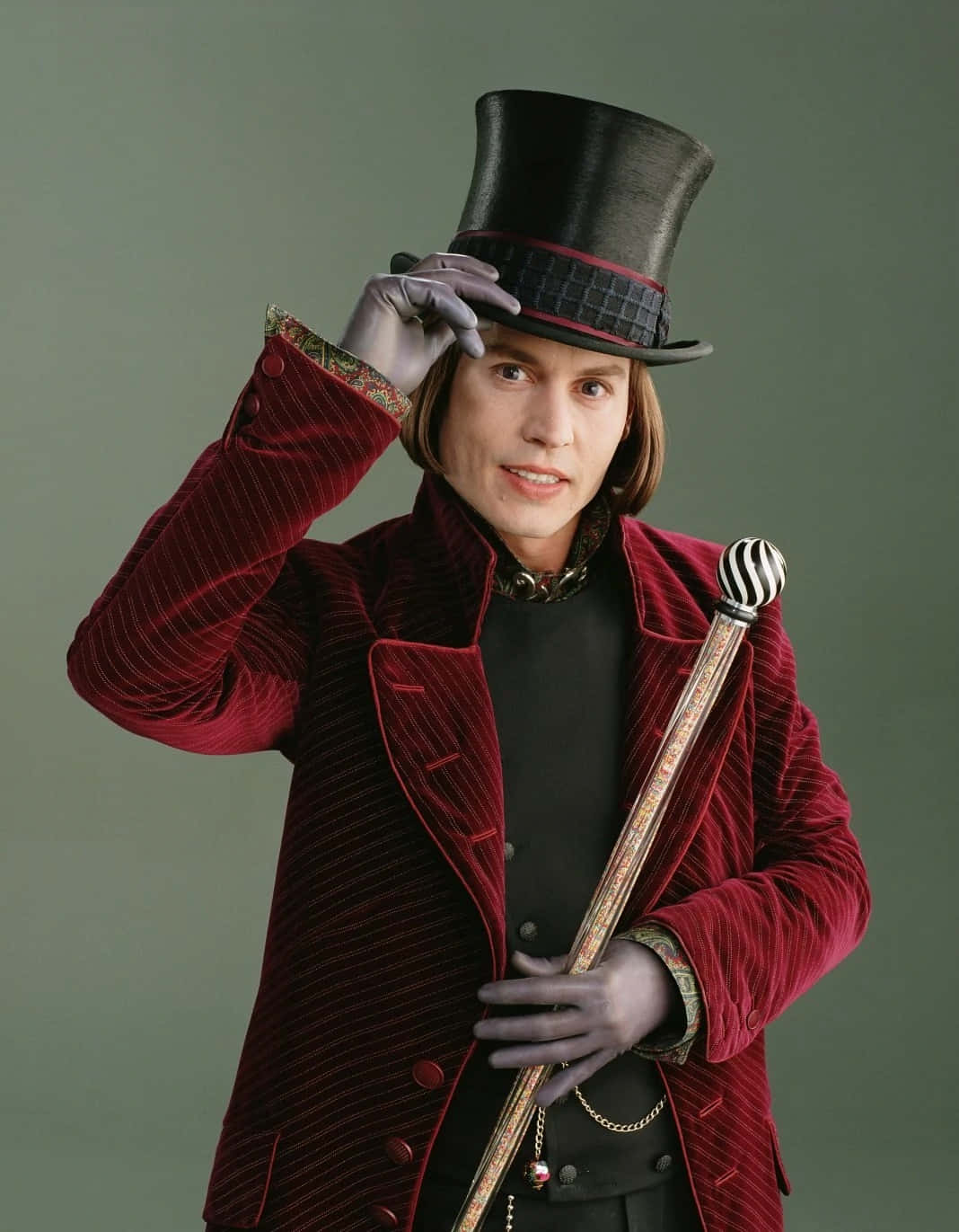 Willy Wonka 桌布 壁紙 — 一個戴紅色天鵝絨高帽和手套的男人，在柔和的綠色背景下，拿著一條條紋手杖擺姿勢。