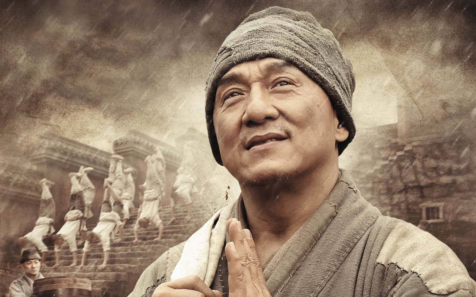 電影 桌布 壁紙 — 一個戴羊毛帽的男人抬頭仰望，表情平靜，身後有僧侶在霧氣瀰漫的懷舊色調場景中登上石階。
