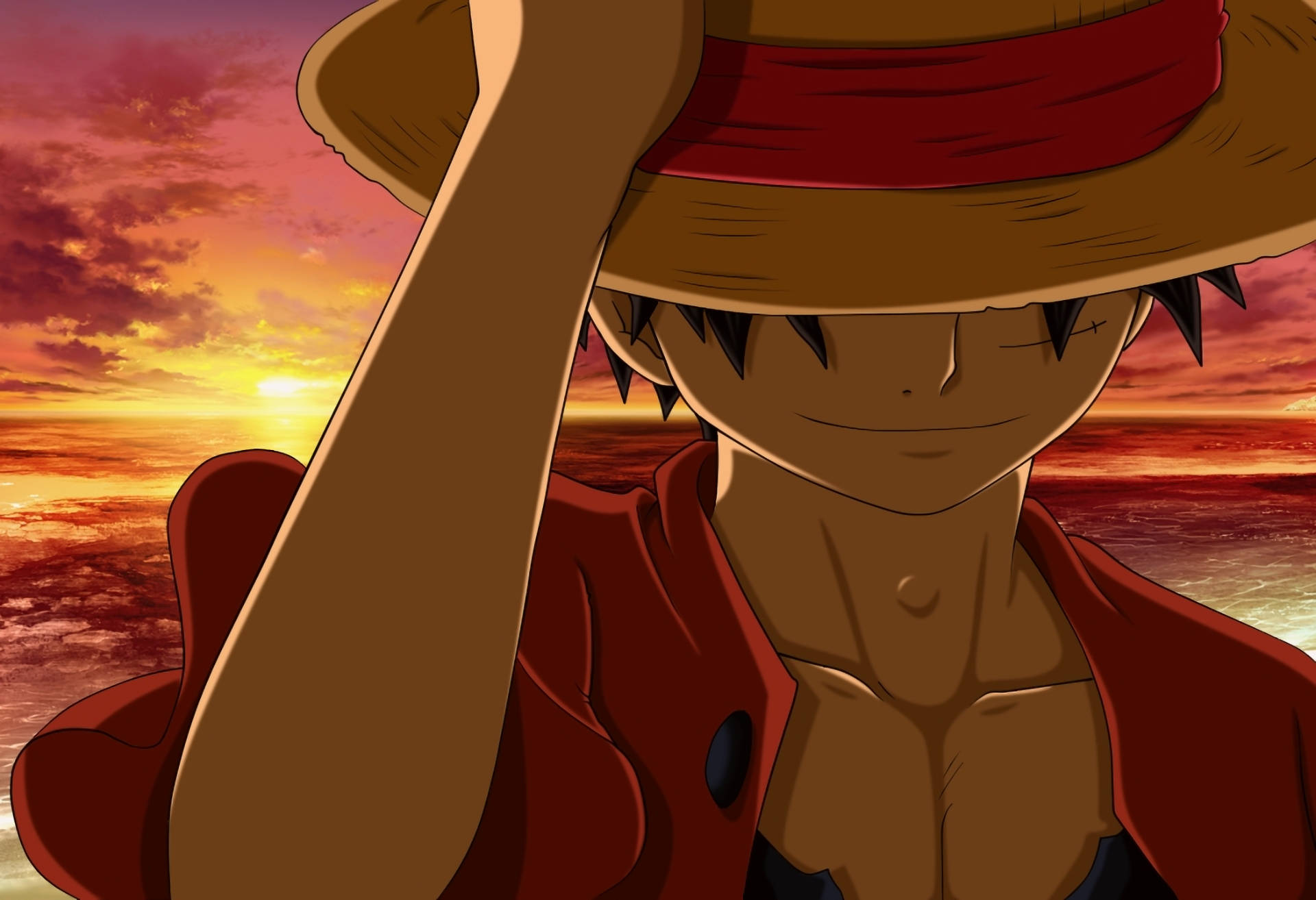 Luffy 桌布 壁紙 — 一個戴草帽、穿紅色外套的動畫男孩微笑著，站在海洋上熾熱的日落前。