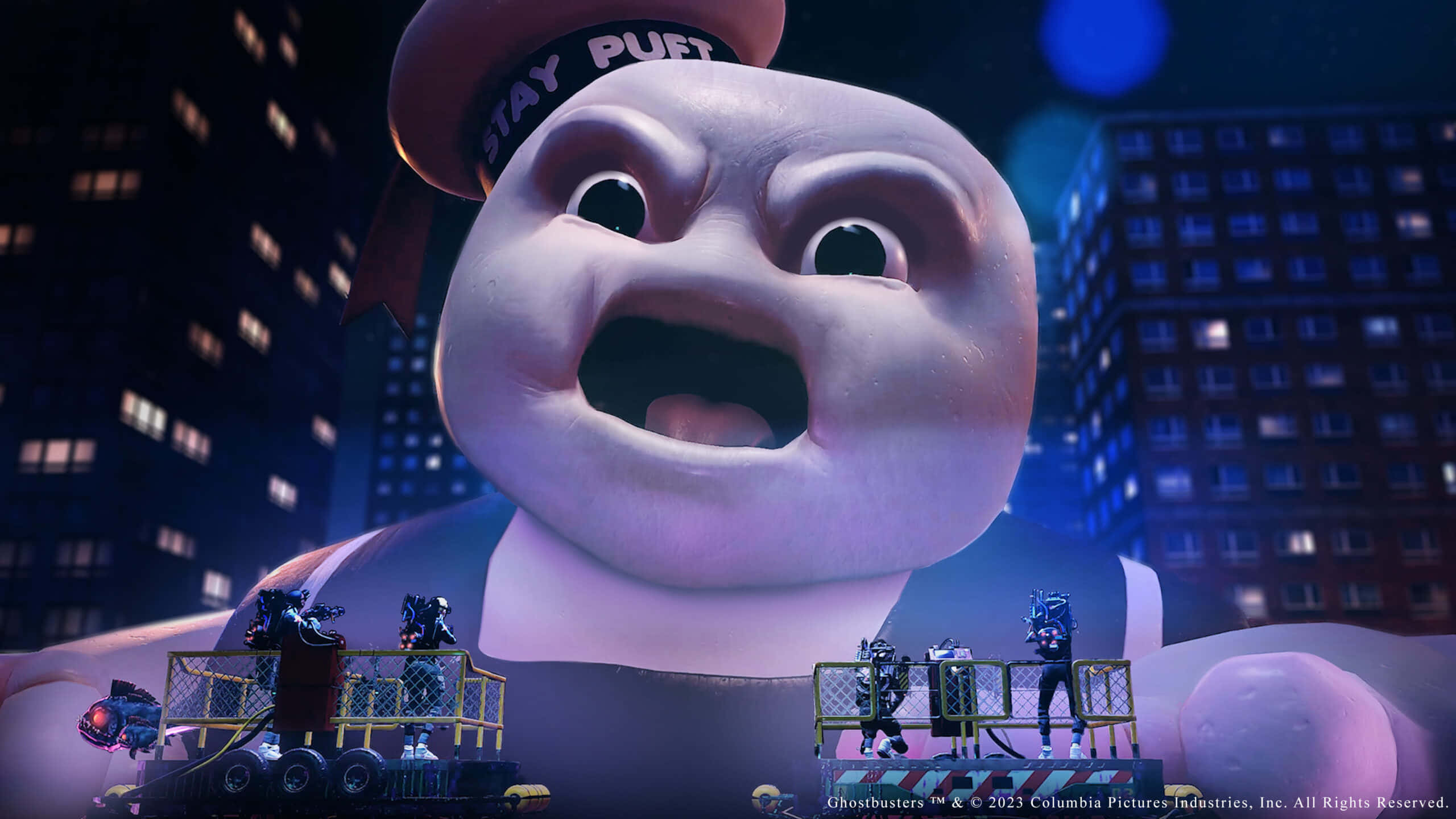 魔鬼剋星 桌布 壁紙 — 一個戴著「Stay Puft」帽子的巨大幽靈吉祥物聳立於城市景觀之上，而魔鬼剋星在夜間騎乘在其手臂上的平台上。