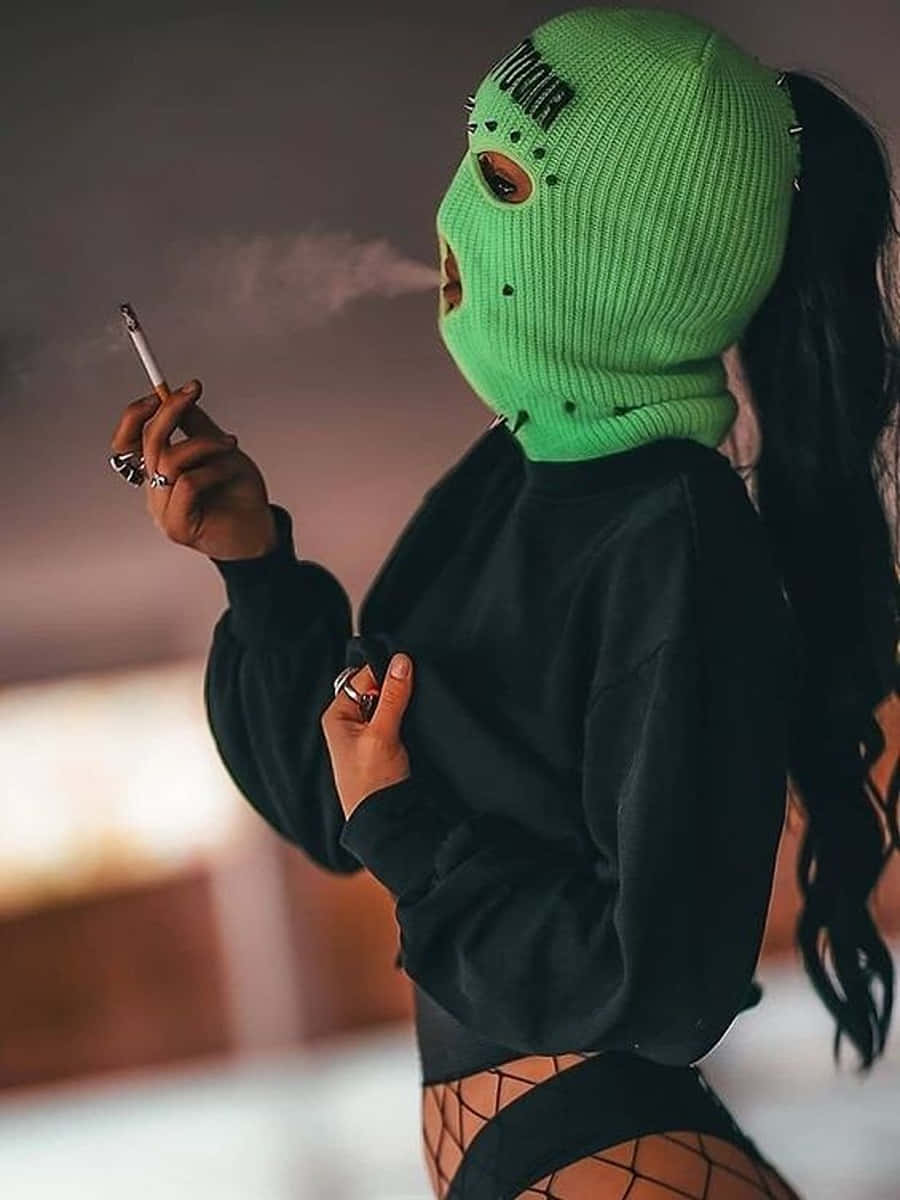 Ski Mask Girl 桌布 壁紙 — 一個戴著亮綠色巴拉克拉法帽的人，穿著黑色連帽衫和漁網襪，正在抽煙。