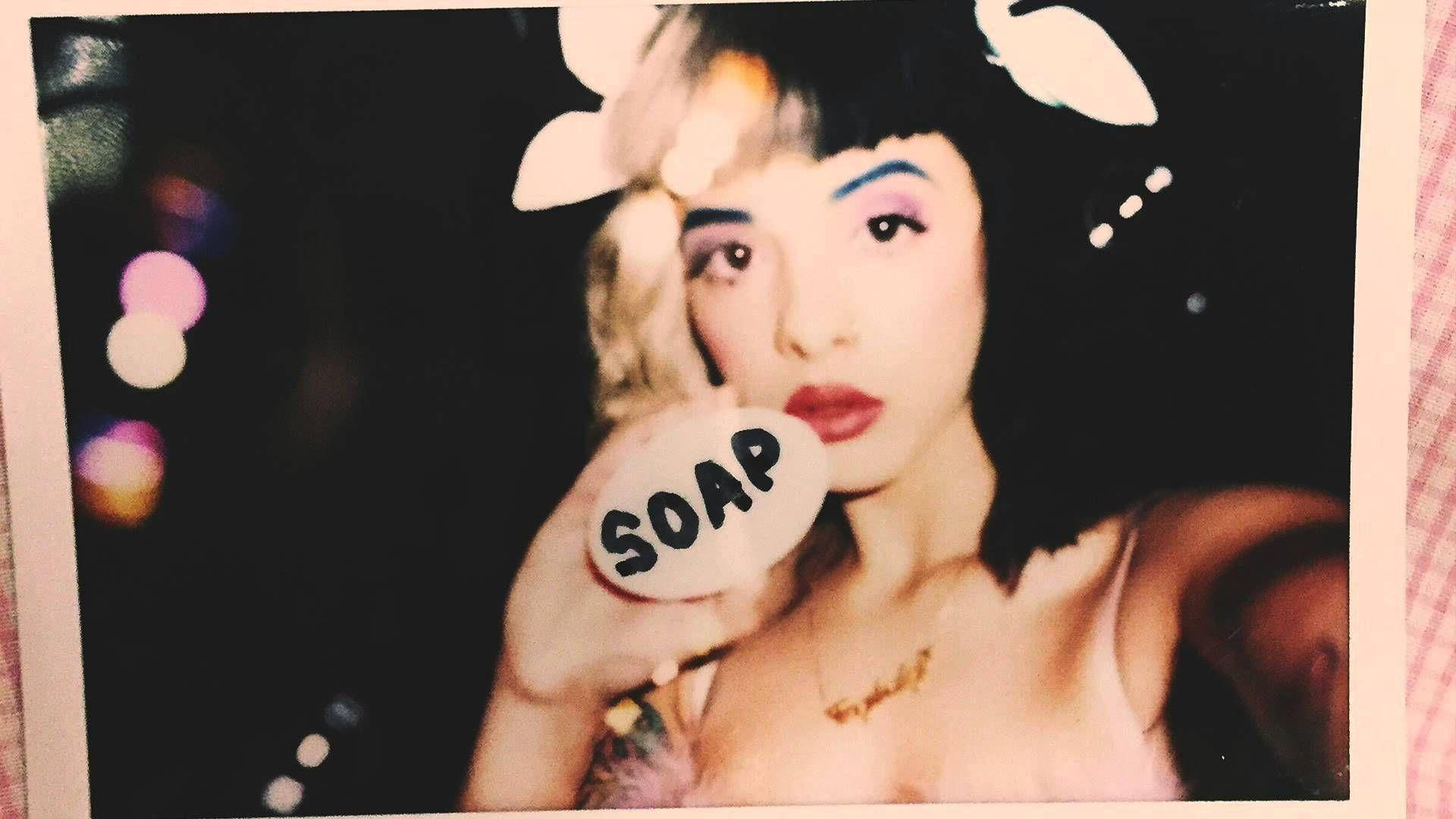 Melanie 桌布 壁紙 — 一個戴著兔耳朵的人拿著一塊標有肥皂的肥皂條，背景是黑暗的，帶有彩色散景燈光。