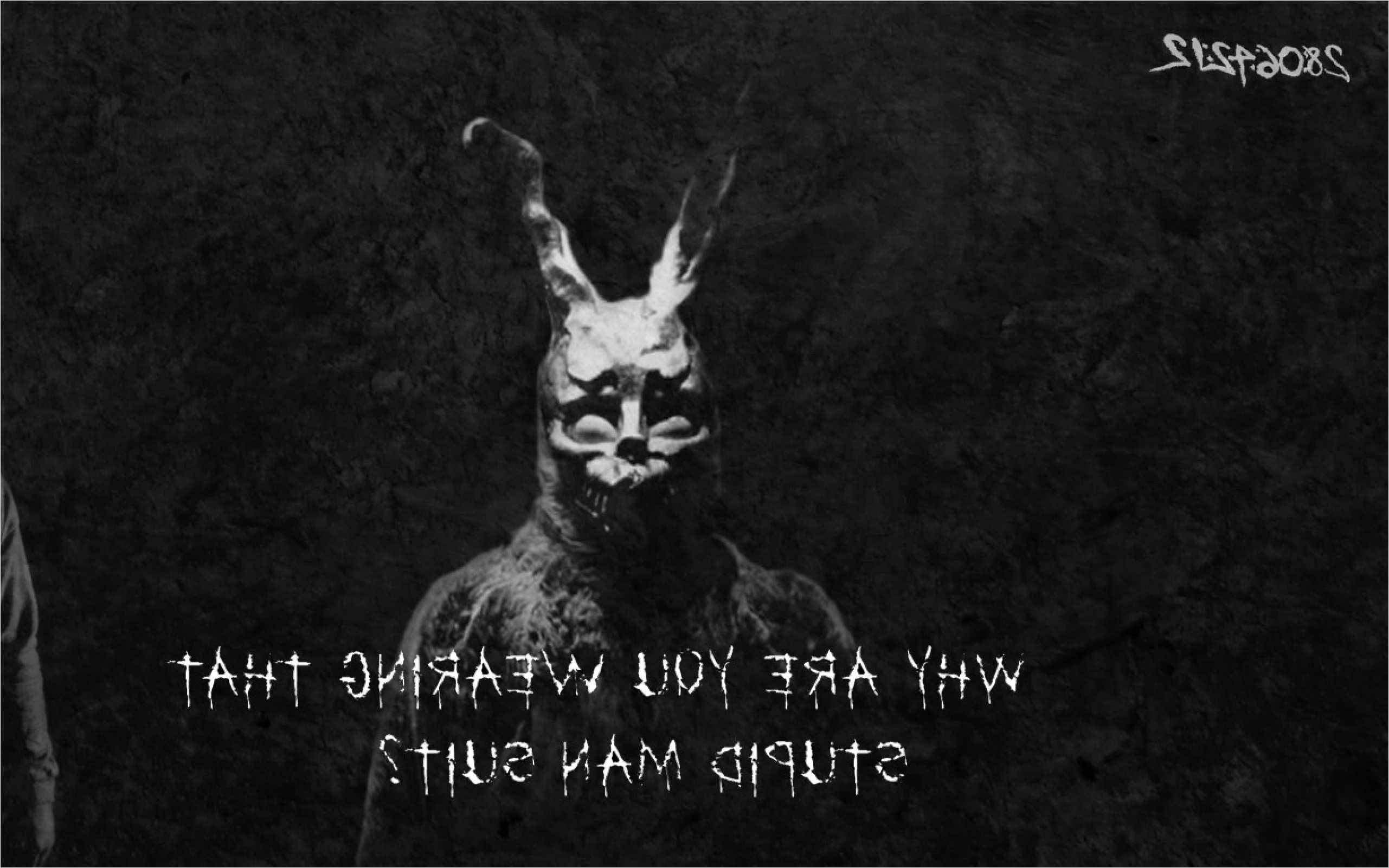Darko 桌布 壁紙 — 一個戴著兔面具的威脅性人物潛伏在黑暗中，伴隨著詭異的白色文字，問為什麼有人穿著愚蠢的男人西裝。