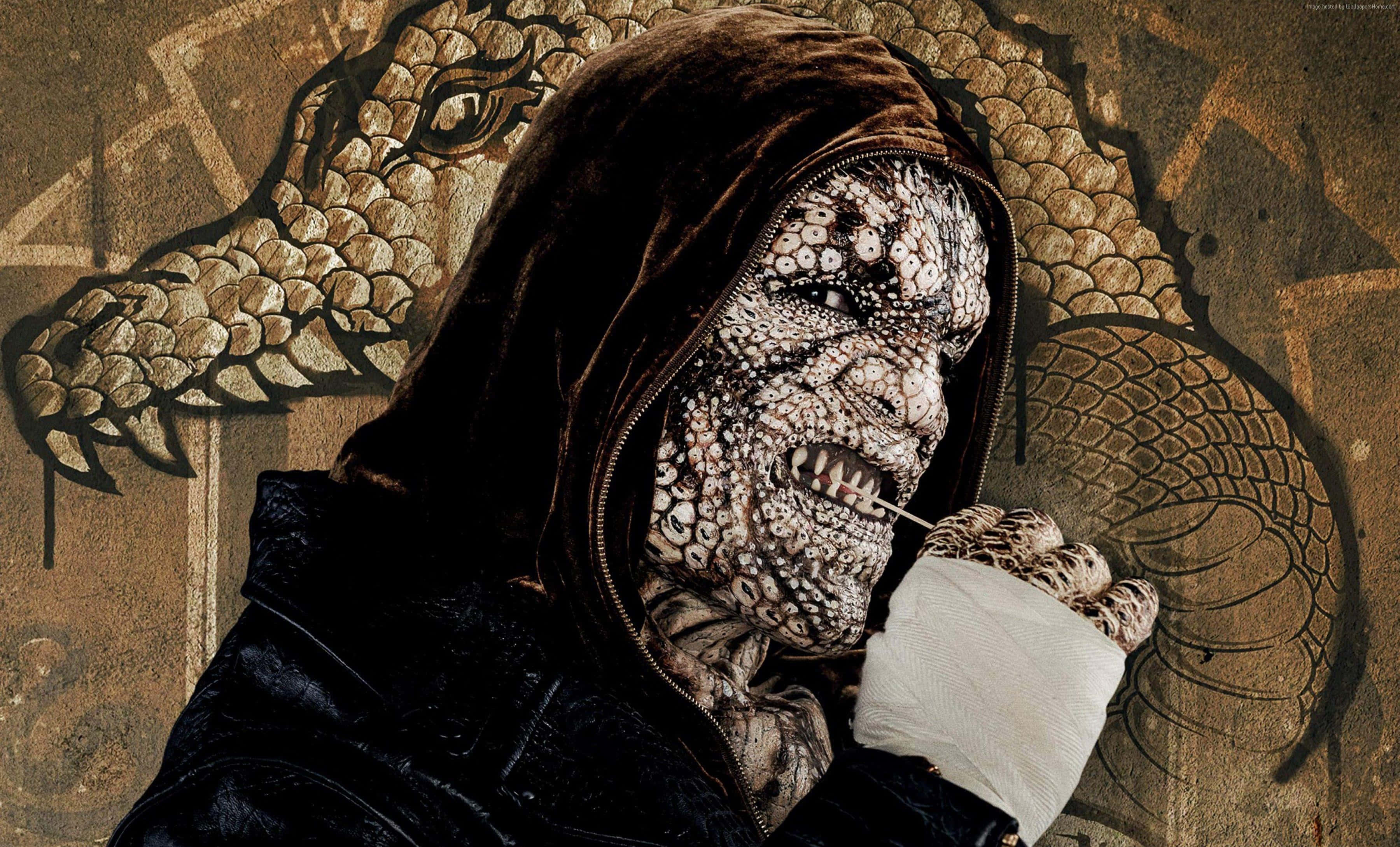 Killer Croc 桌布 壁紙 — 一個戴著兜帽、擁有紋理爬蟲類皮膚和露出牙齒的人物，站在一幅以大地色調繪製的盤龍壁畫前。
