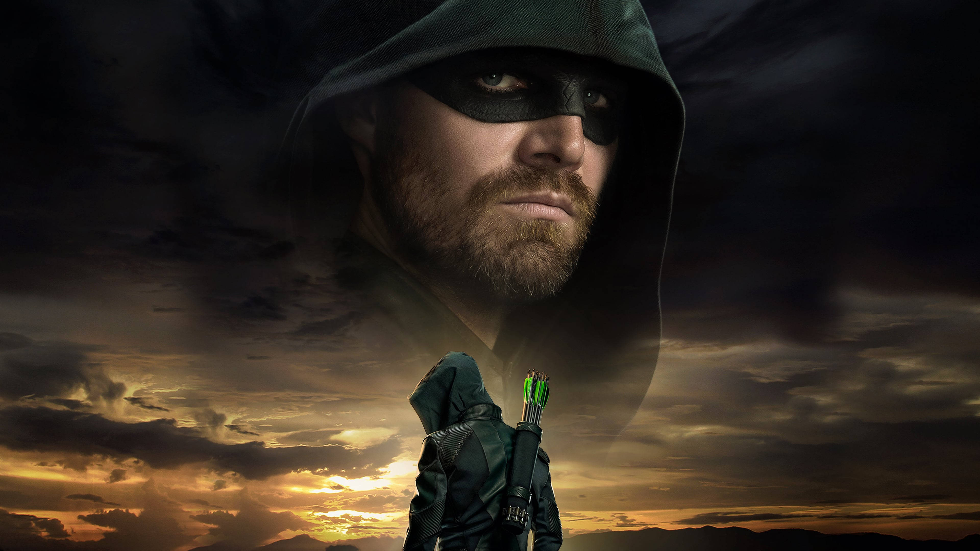 Green Arrow 桌布 壁紙 — 一個戴著兜帽的弓箭手在戲劇性的日落天空下以剪影站立，一個巨大的幽靈面孔懸浮在他上方。