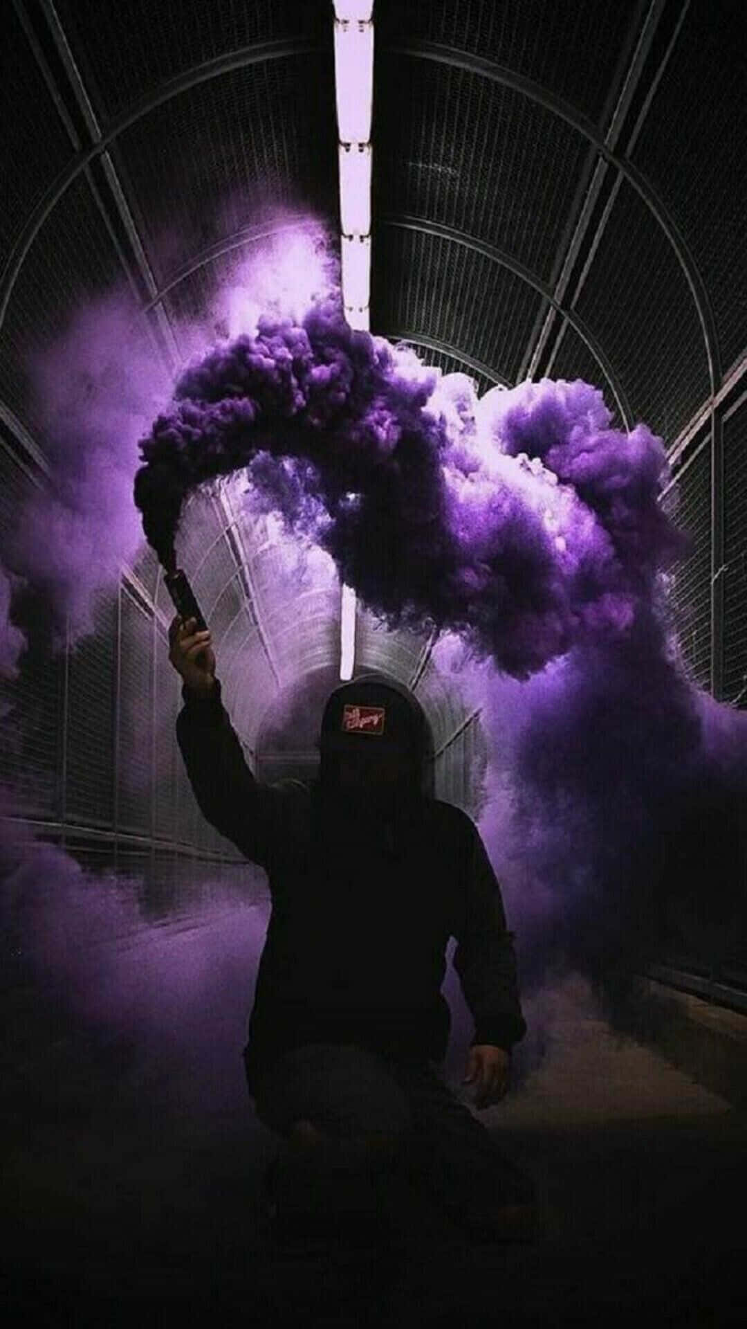 Cool Smoke 桌布 壁紙 — 一個戴著兜帽的身影在黑暗隧道中，於單一明亮頂燈下釋放出鮮豔的紫色煙霧彈。