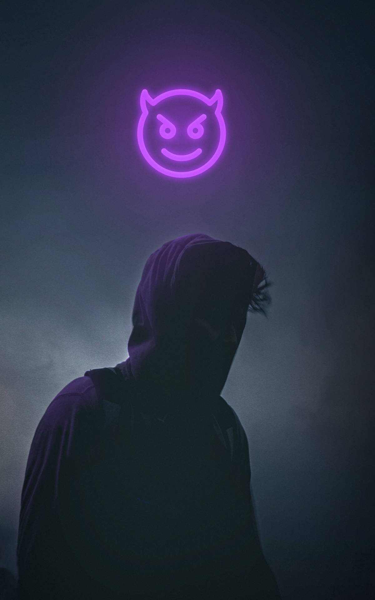 Devil Horns 桌布 壁紙 — 一個戴著兜帽的身影站在陰影中，下方是發光的紫色惡魔表情符號霓虹燈牌，房間煙霧瀰漫、昏暗。