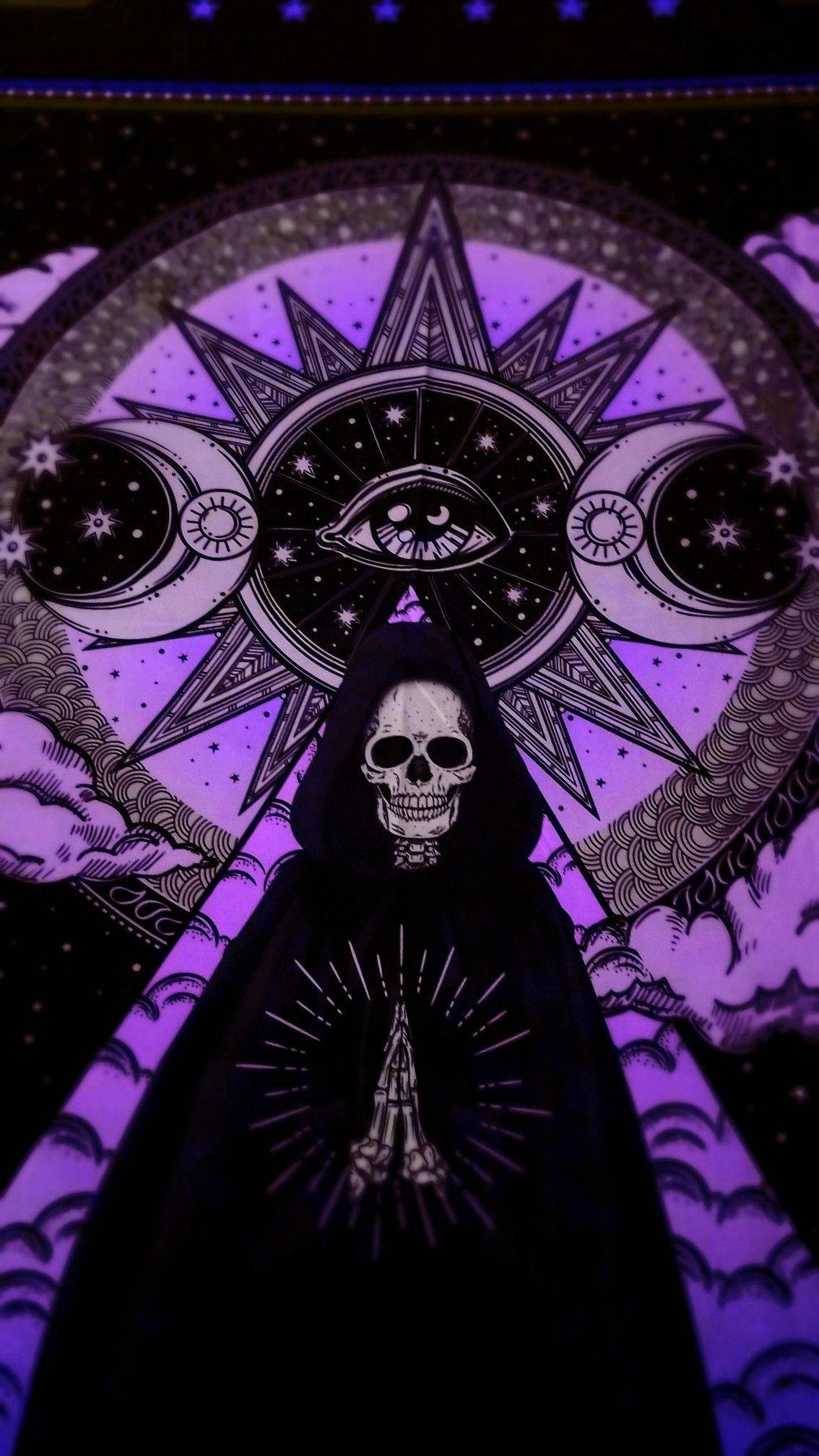 Goth Aesthetic 桌布 壁紙 — 一個戴著兜帽的骷髏身影站在一個宇宙符號前，符號中有一隻全視之眼，兩側有新月，背景是紫色的星空。