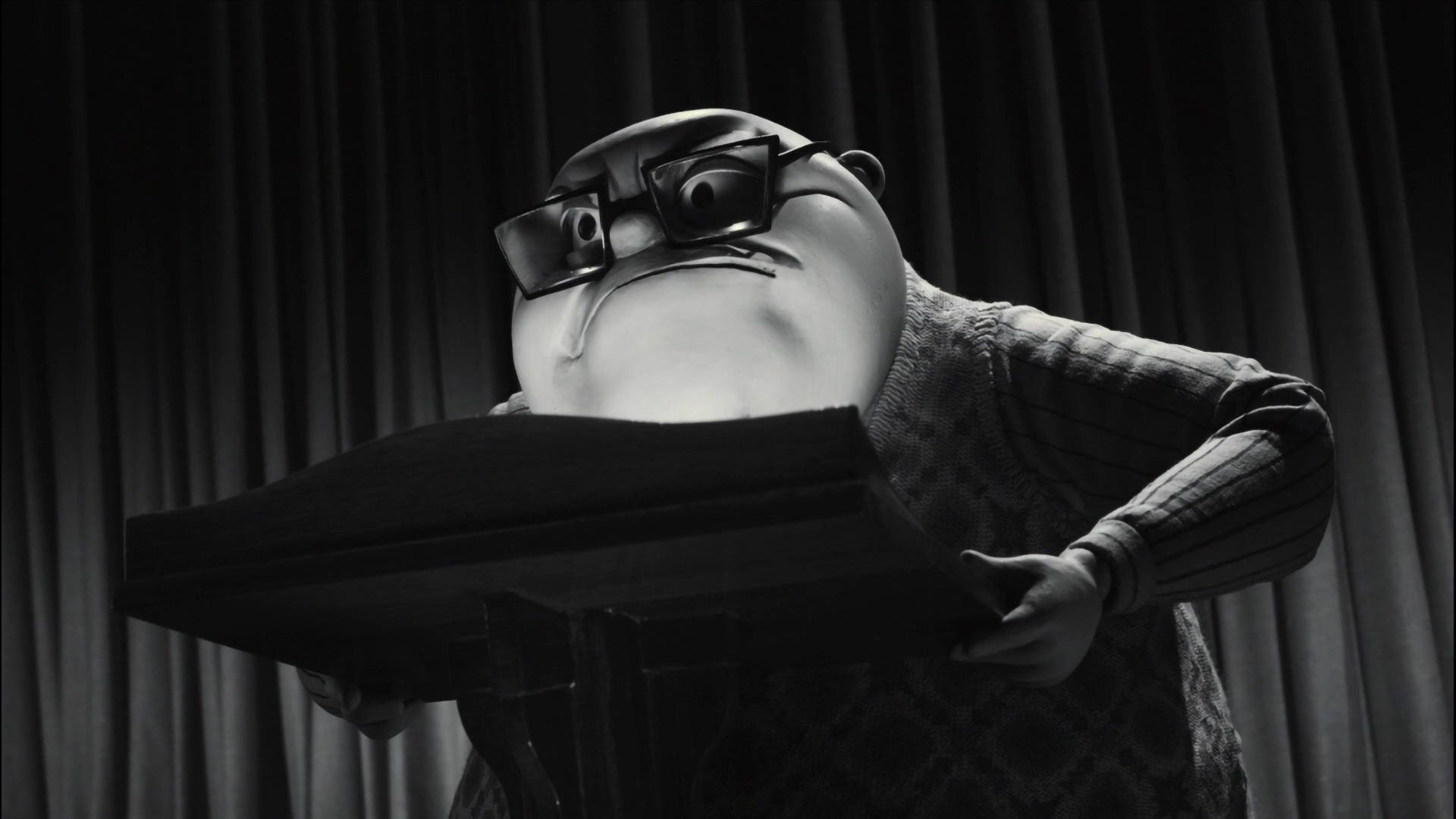 Frankenweenie 桌布 壁紙 — 一個戴著厚眼鏡和鬍子的黑白動畫角色，靠在講台上，背景是窗簾。