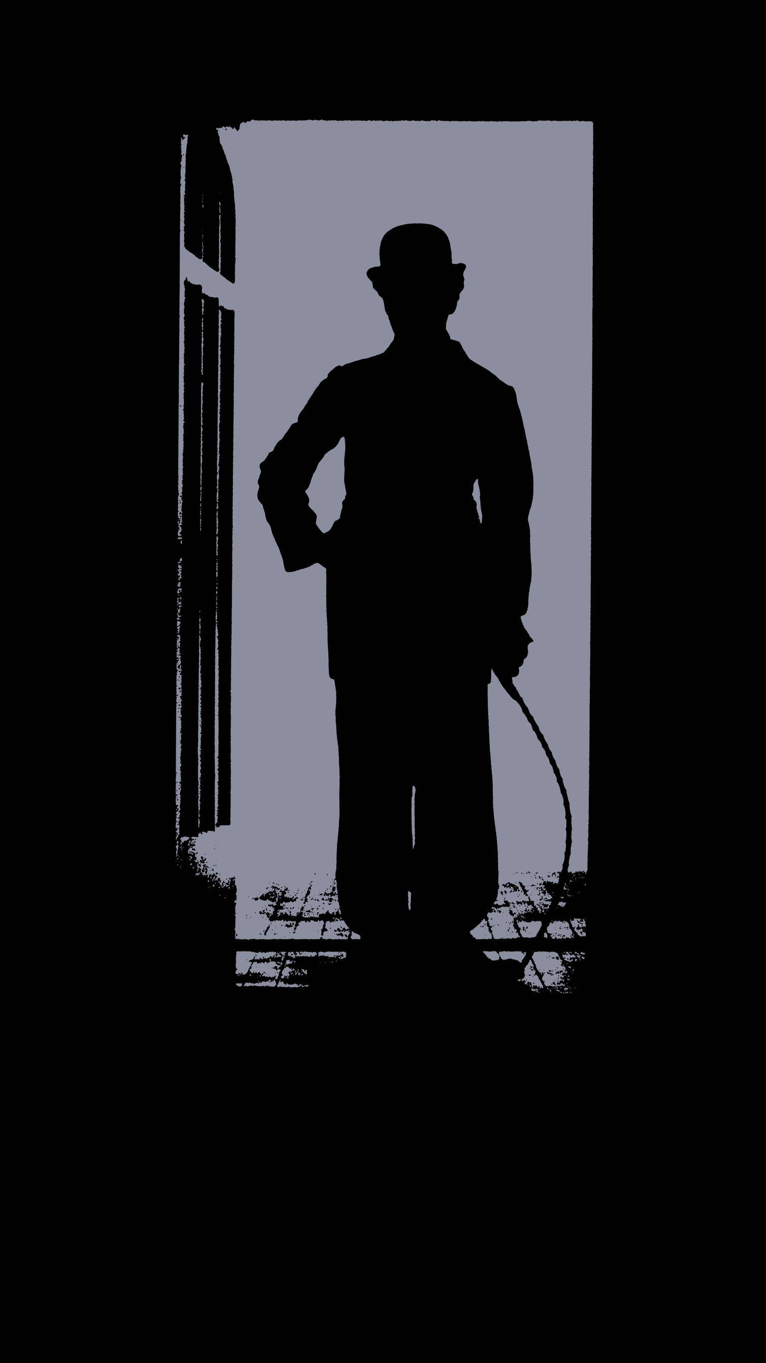 Chaplin 桌布 壁紙 — 一個戴著圓頂禮帽和手杖的男人的清晰剪影，站在門口，背景是柔和的藍灰色。