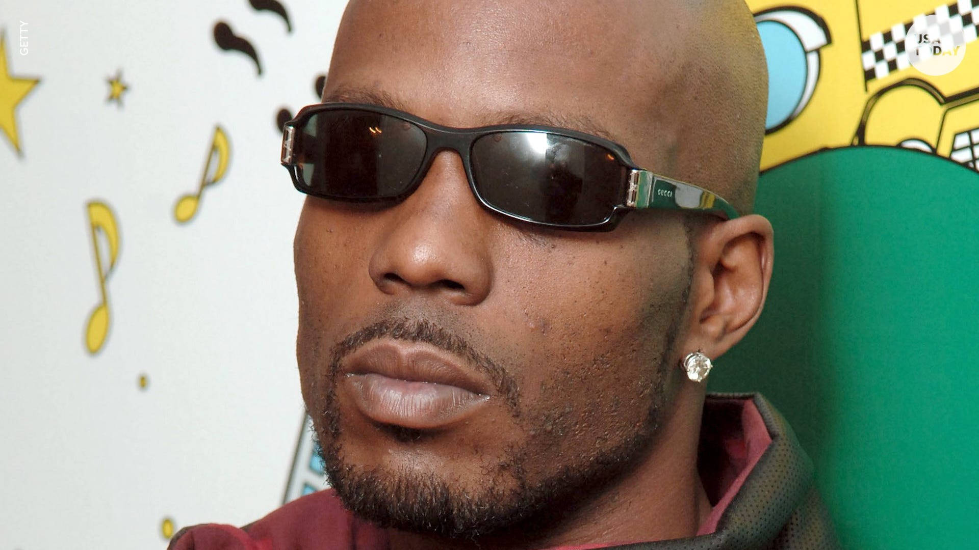 Dmx 桌布 壁紙 — 一個戴著太陽眼鏡和耳環的男人坐在色彩繽紛的卡通主題牆前，牆上有音符和星星。