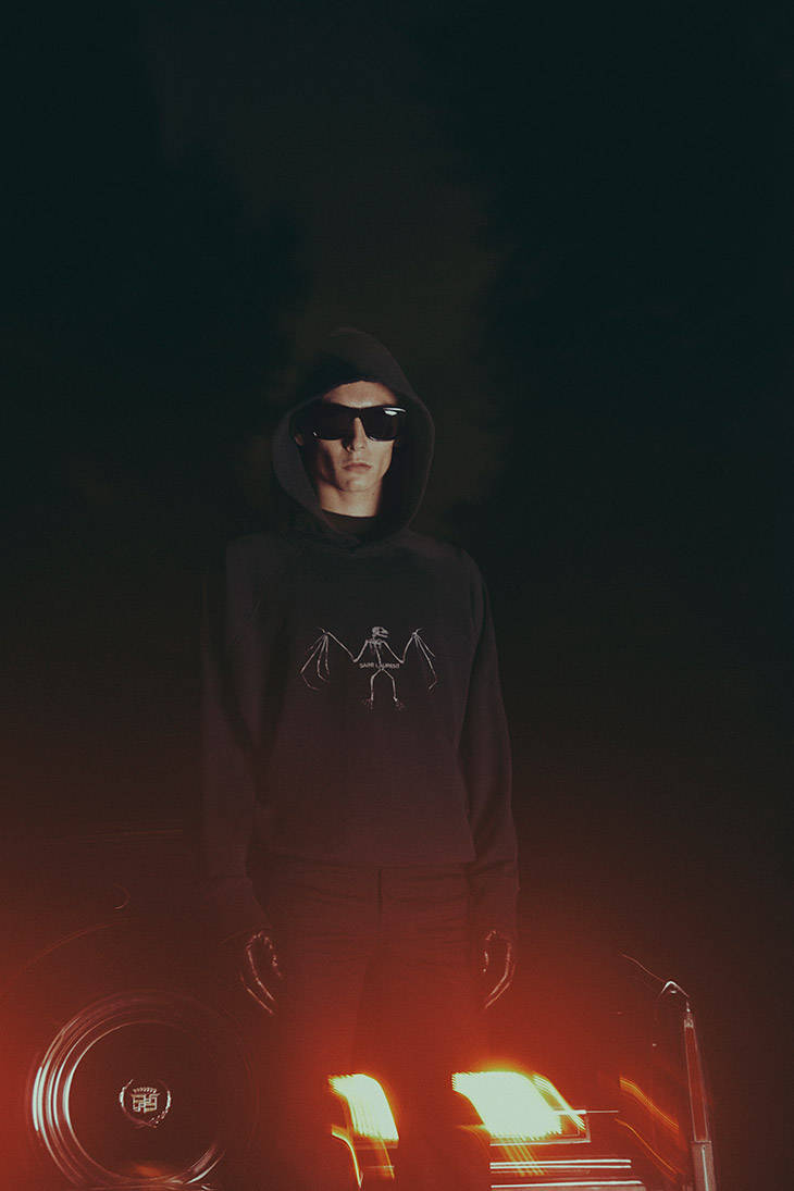 Sunglasses 桌布 壁紙 — 一個戴著太陽眼鏡的連帽人物站在煙霧瀰漫的黑暗環境中，面前是發光的車頭燈。